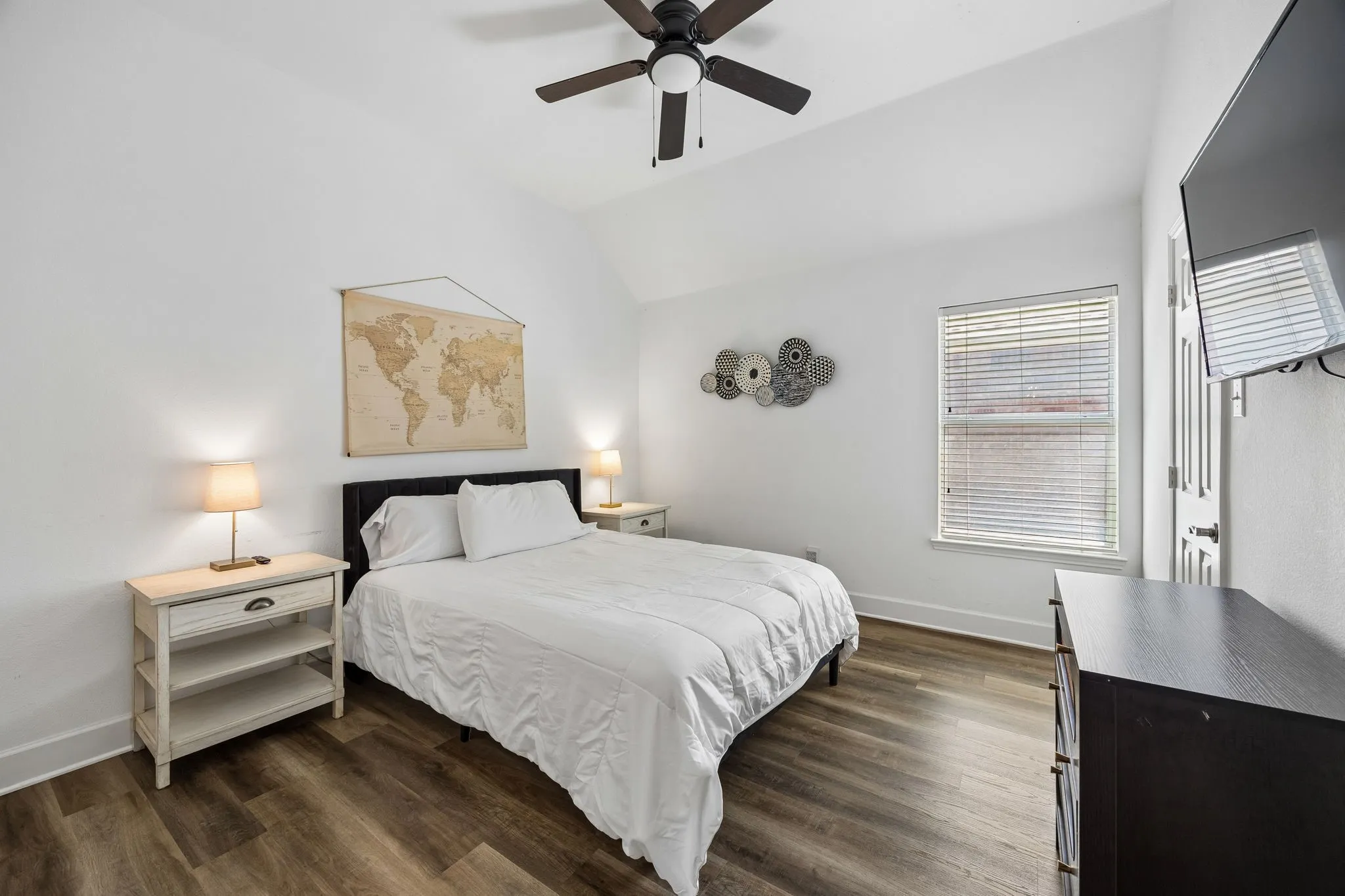 Vaulted ceilings with a ceiling fan, wood-finish flooring, and a window with blinds