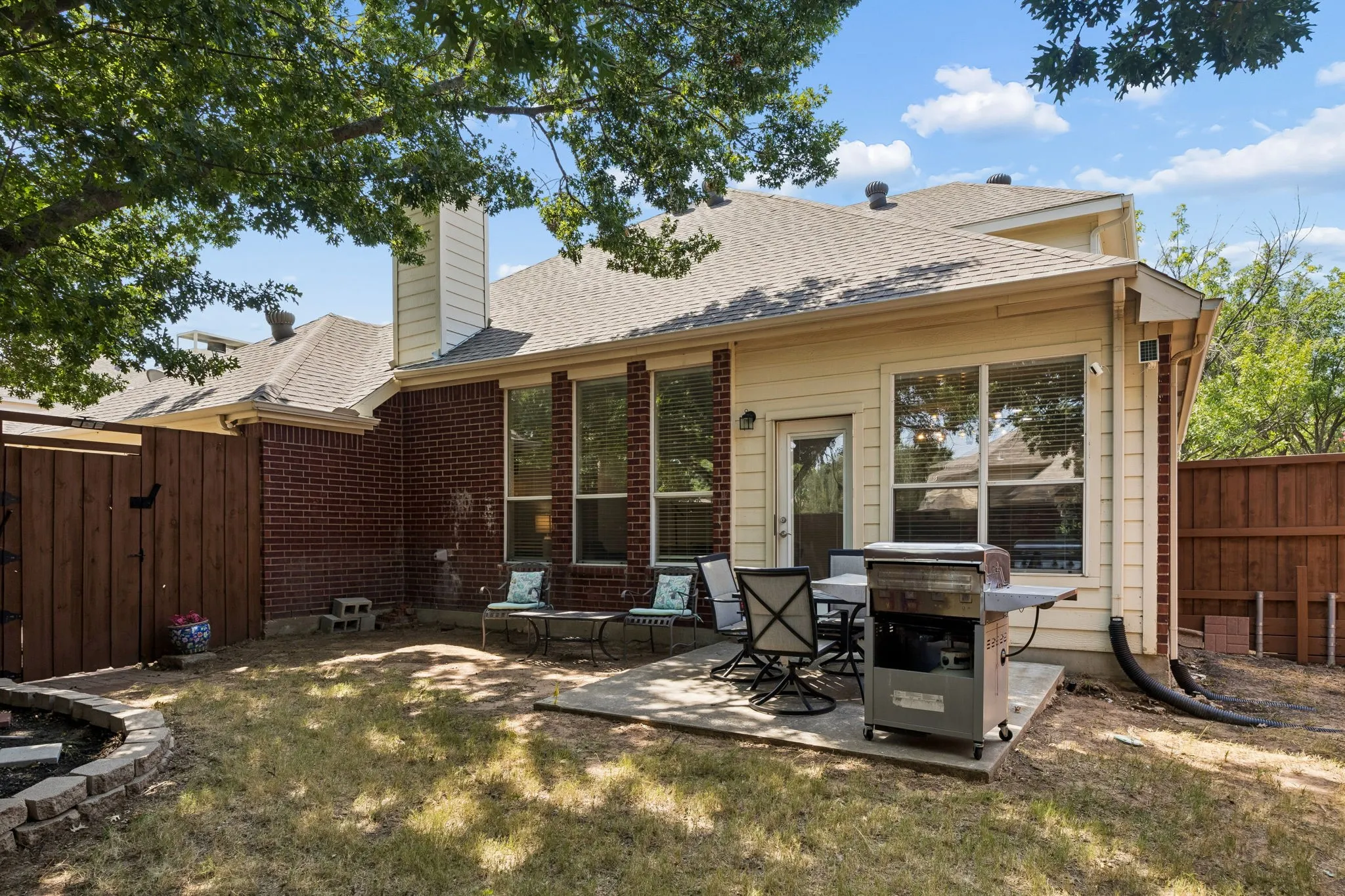 Exterior brick accents, siding, and a private fenced yard with a concrete patio