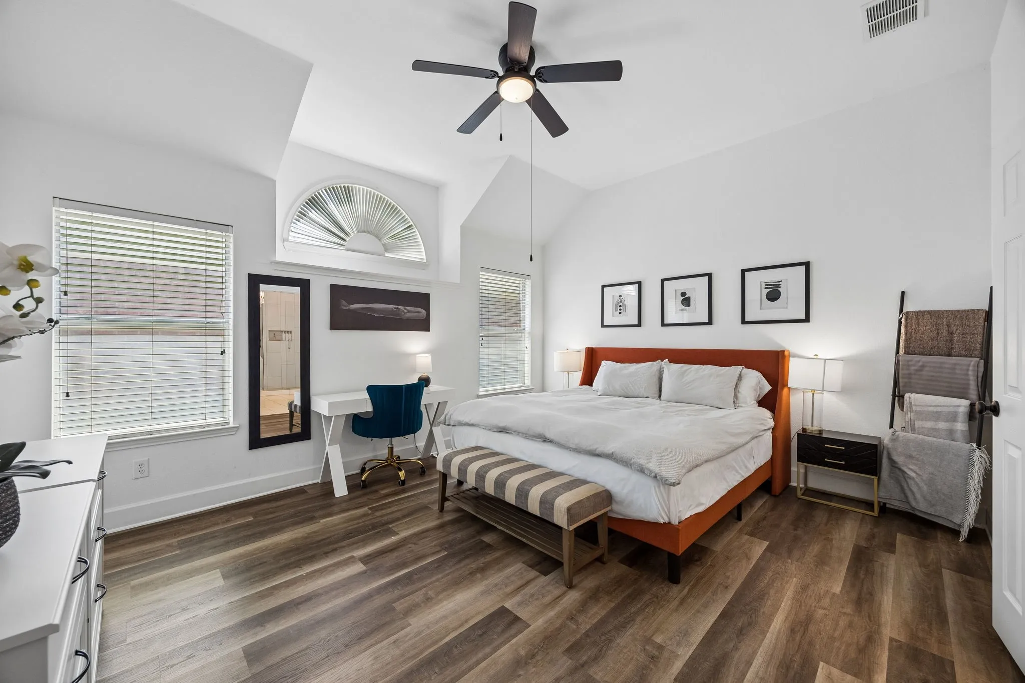 Vaulted ceiling with a ceiling fan, wood-finish flooring, multiple windows with blinds, and an arched transom window