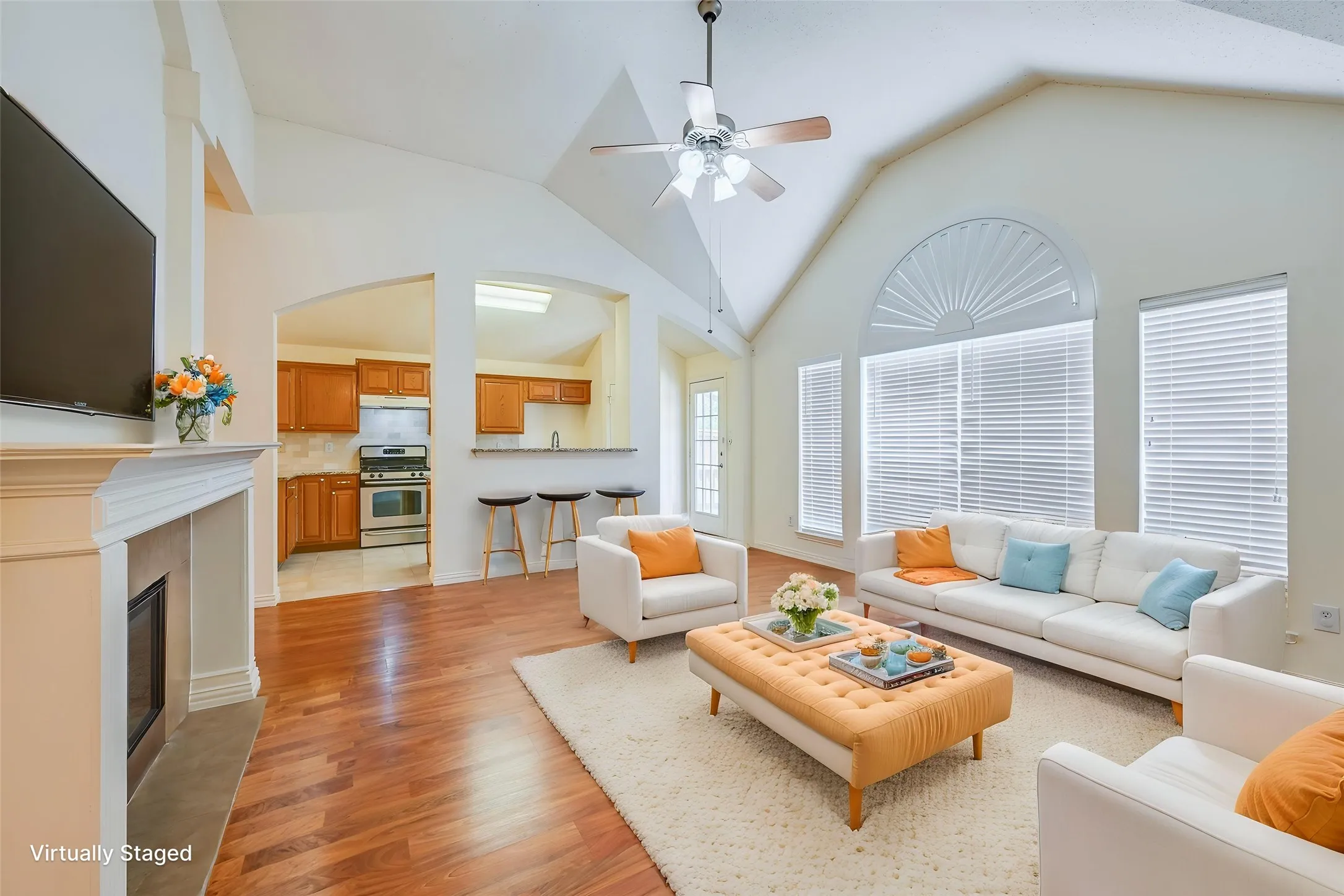 Vaulted ceilings with a ceiling fan, recessed fireplace with mantel, wood-finish flooring, and arched window with fanlight