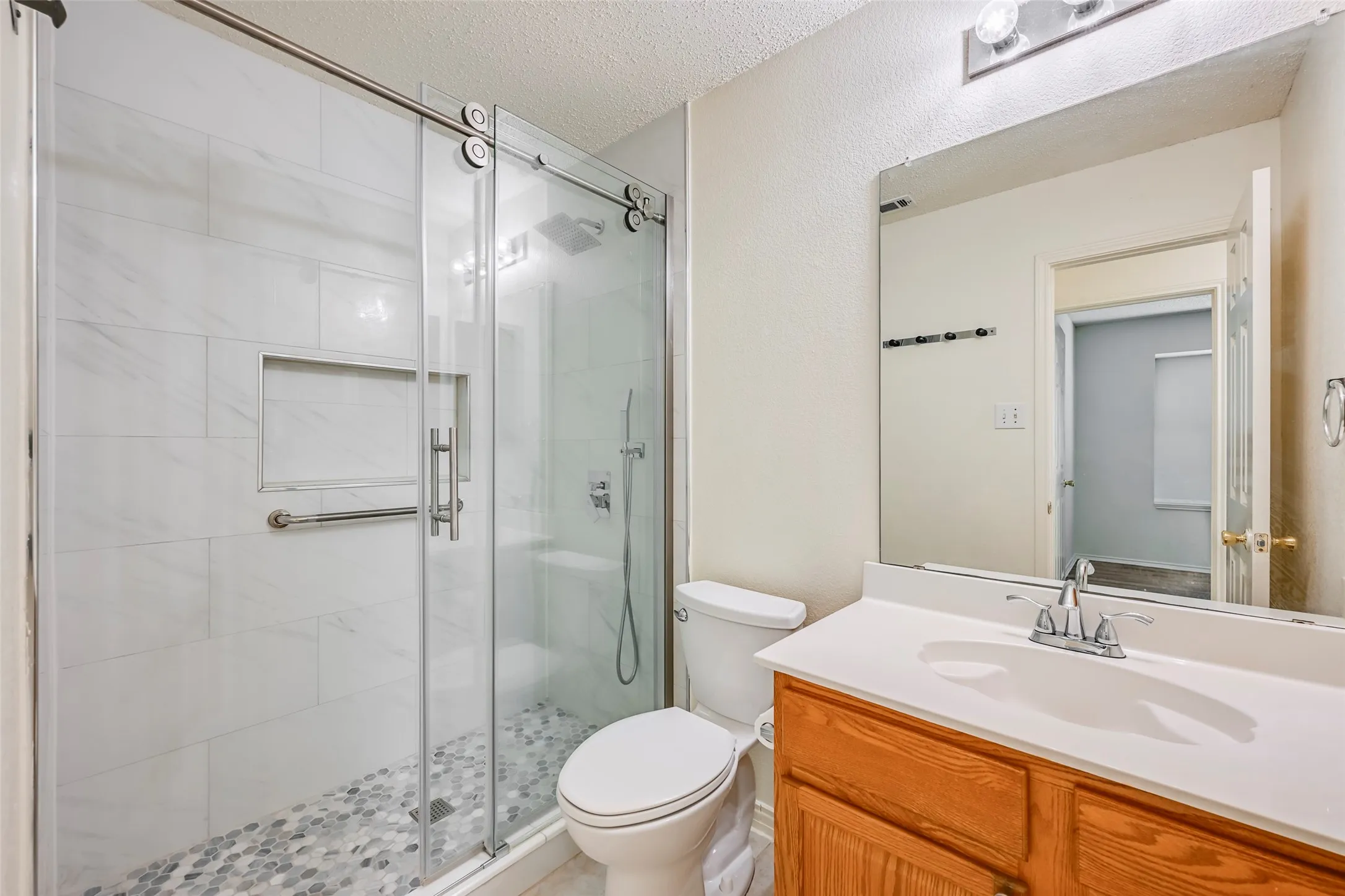 Walk-in shower with clear glass enclosure and tile surround