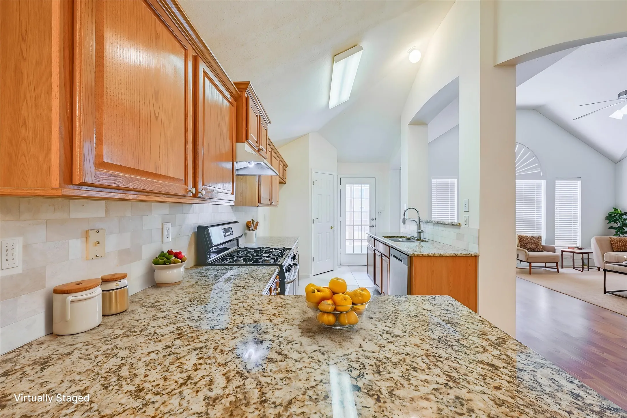 Kitchen featuring granite countertops, wood cabinetry, stainless steel gas range, and a tile backsplash