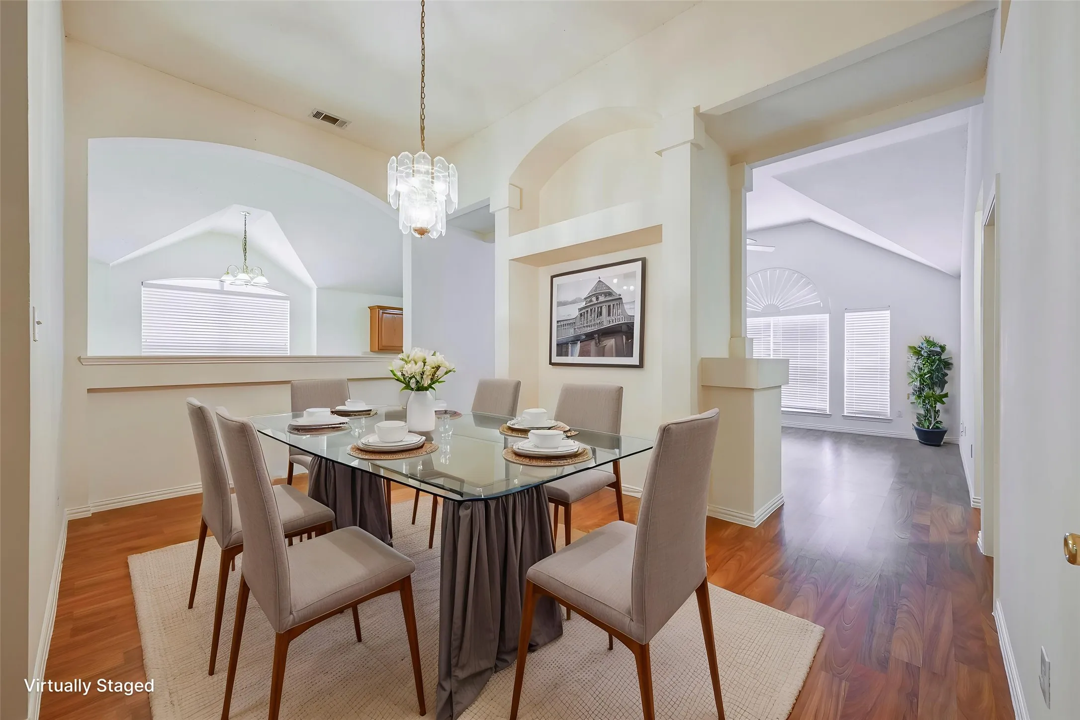 Vaulted ceilings, wood-finish flooring, arched doorways, and a contemporary chandelier