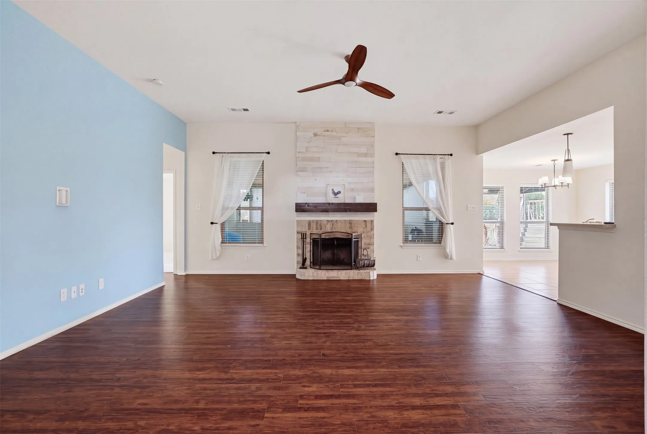 Wood-finish flooring, vaulted ceiling, and a cozy fireplace with a wood mantel