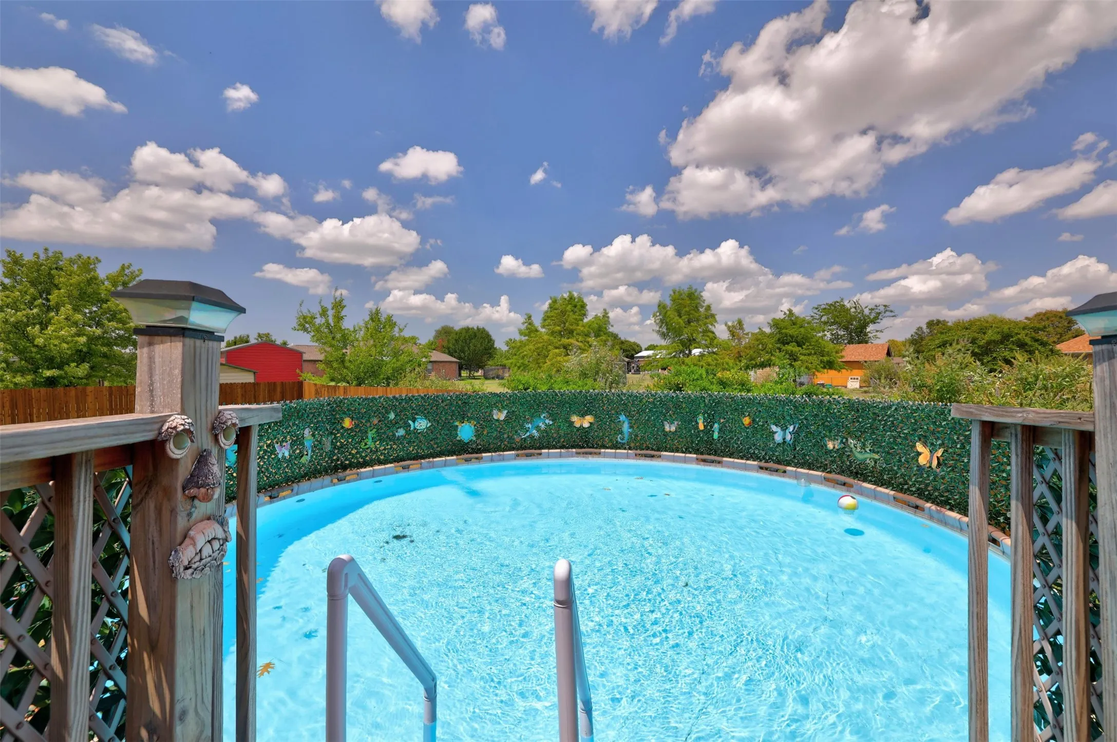 Above-ground sparkling swimming pool with integrated entry steps and a surrounding privacy fence