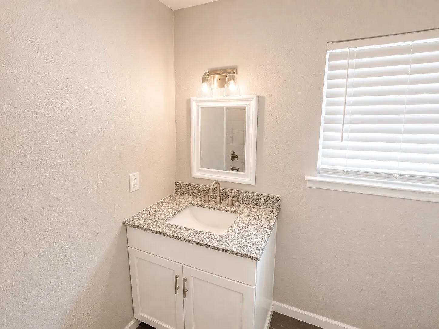 White vanity with a granite-style countertop and integrated sink