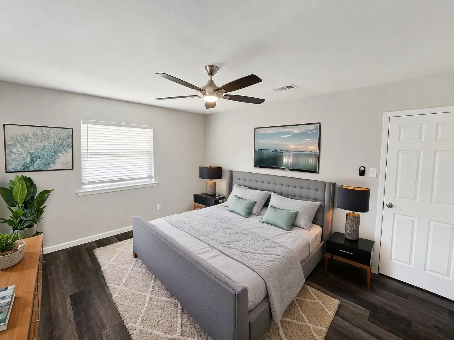 Virtually staged
Wood-finish flooring, ceiling fan with integrated lighting, window with blinds, paneled interior door, and light gray wall paint