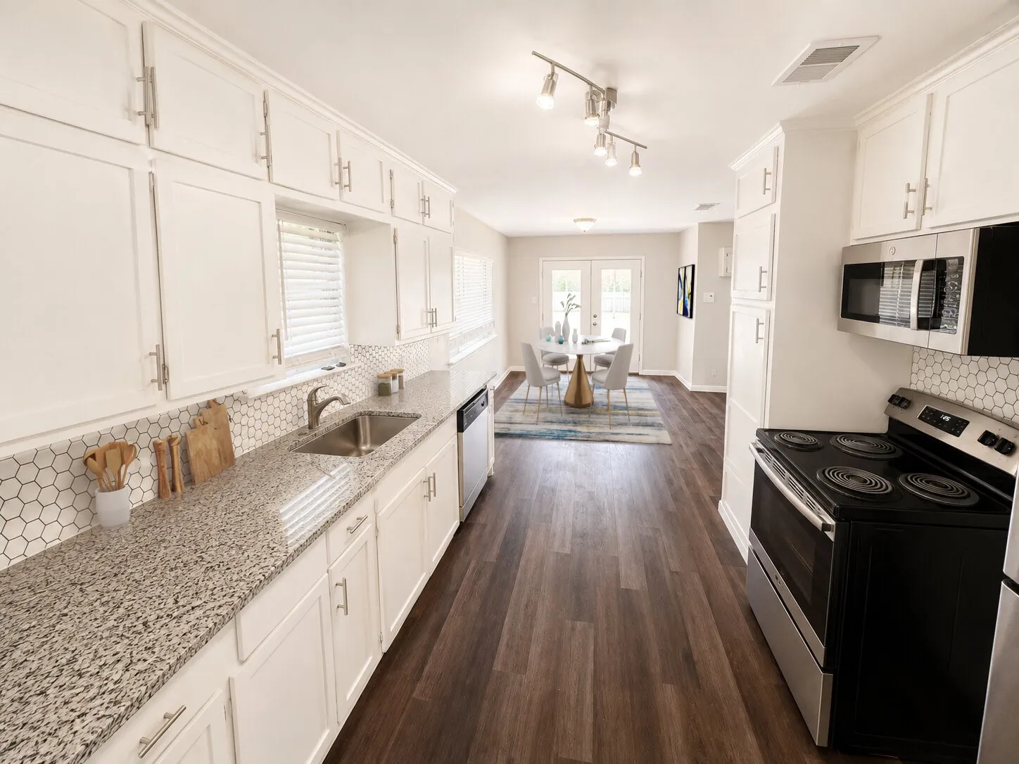 Virtually staged
White cabinetry with brushed nickel hardware, speckled countertops, honeycomb tile backsplash, stainless steel appliances, and wood-finish flooring