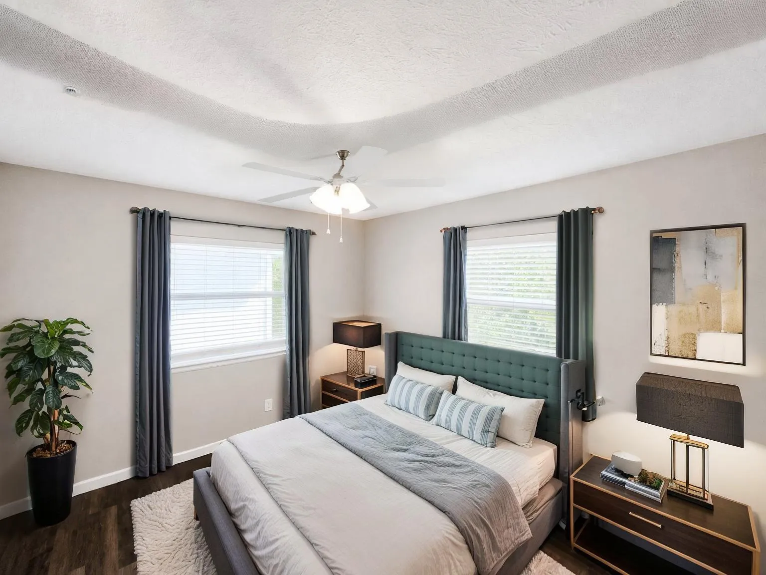 Virtually staged
Tray ceiling with a ceiling fan, two windows with blinds, and dark wood-finish flooring