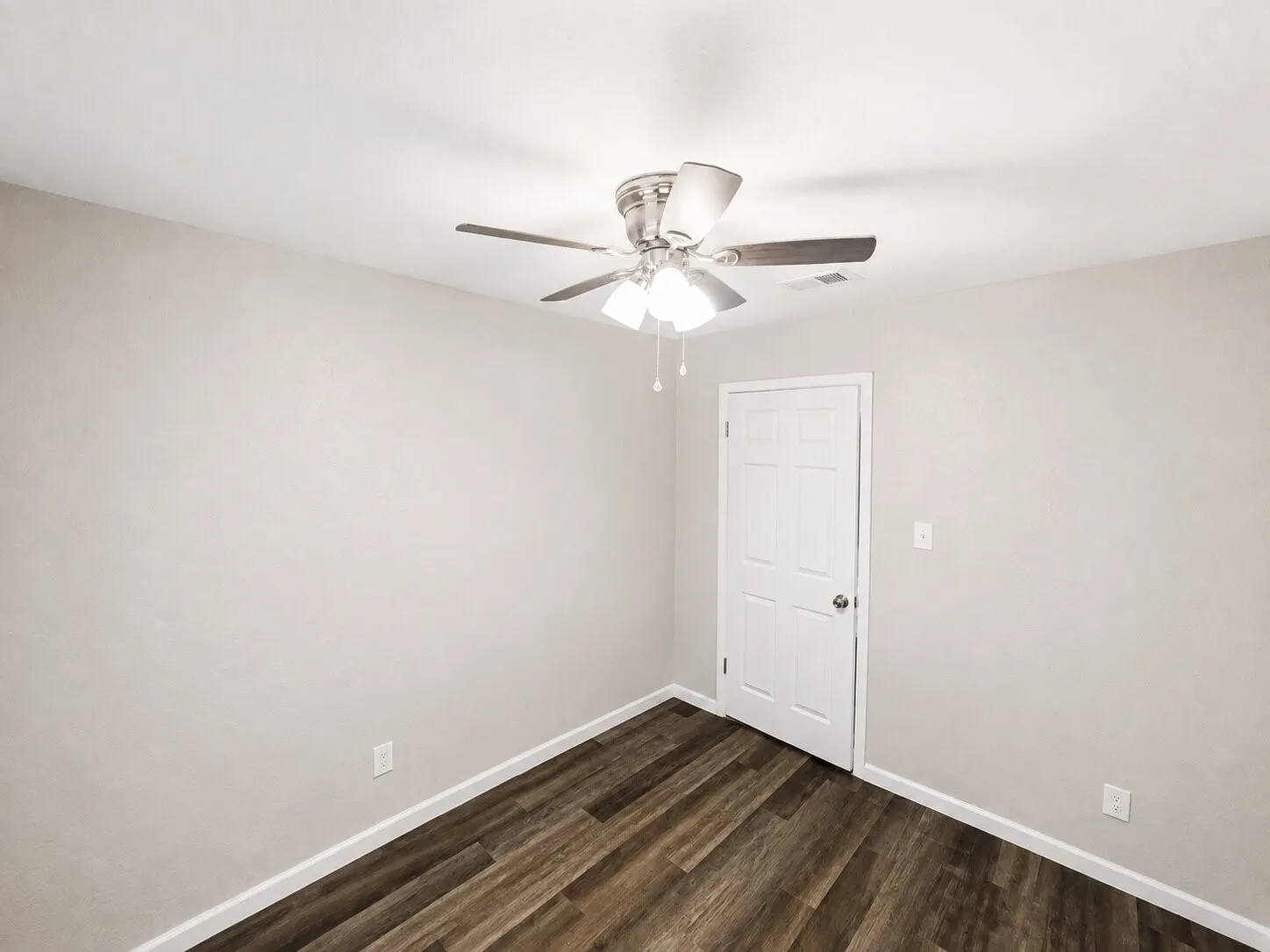 Wood-finish flooring, white walls, and a ceiling fan with integrated lighting