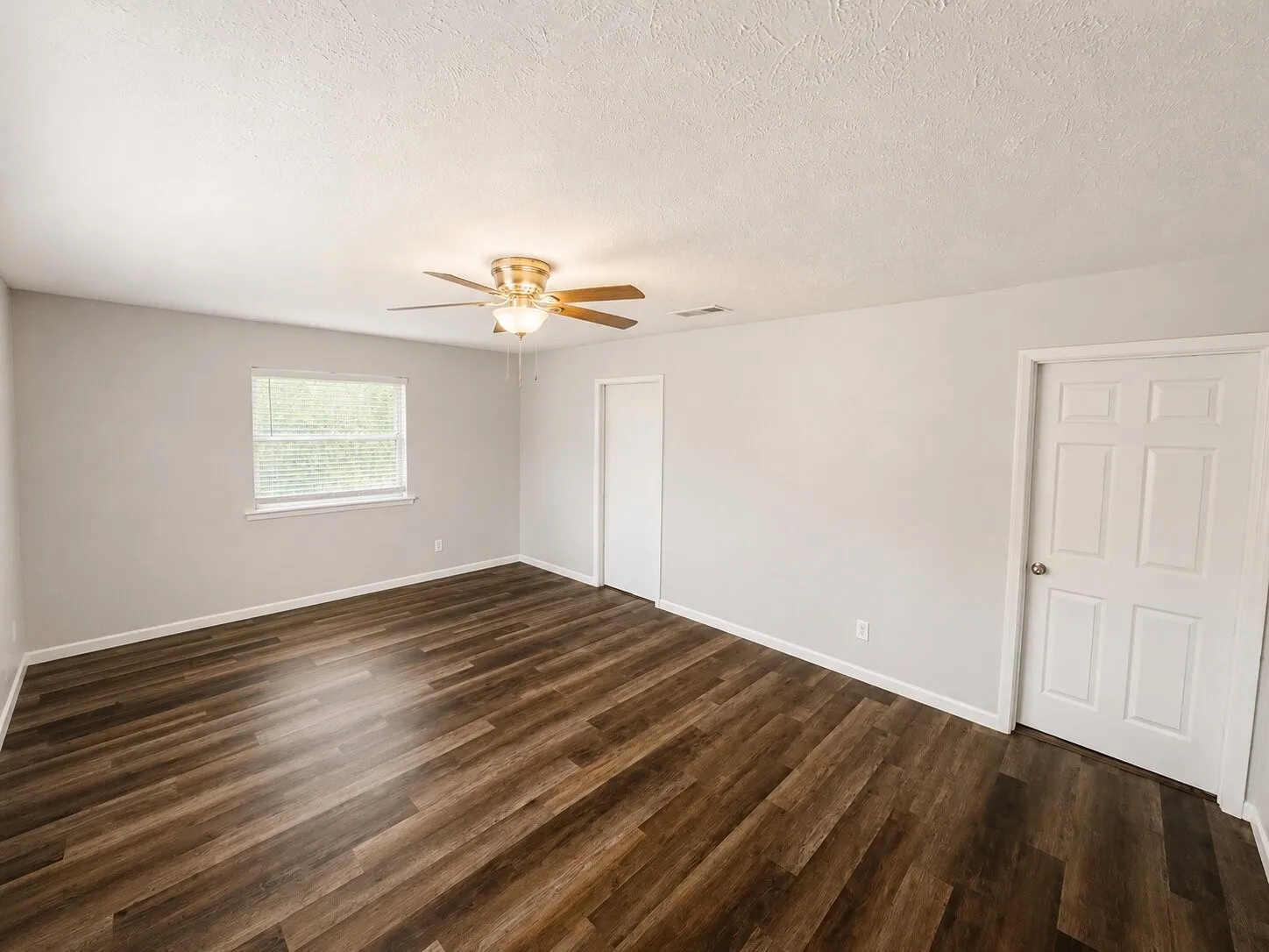 Wood-finish flooring, light gray walls, white trim, ceiling fan with integrated lighting, and a window with horizontal blinds