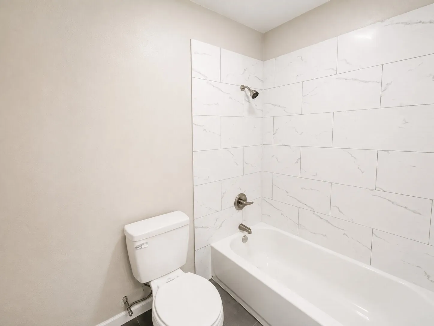 Bathtub with brushed nickel fixtures and white rectangular tile surround