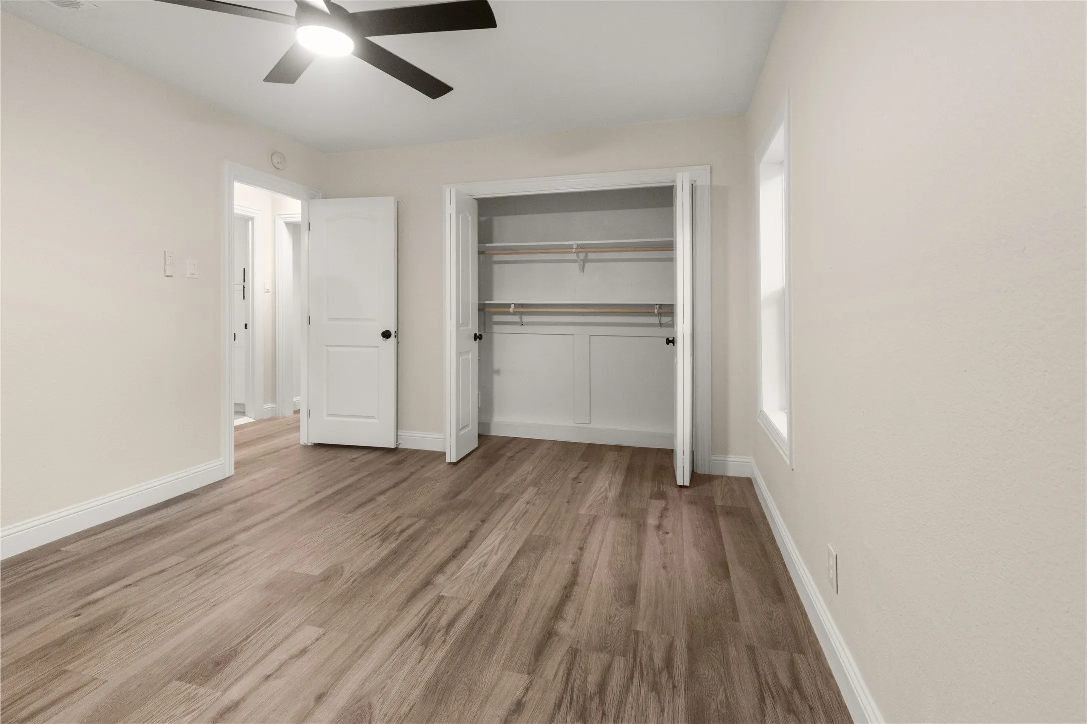 Bedroom #1 with wood-finish flooring, large closet, a ceiling fan with integrated lighting, and three windows for lots of natural light.