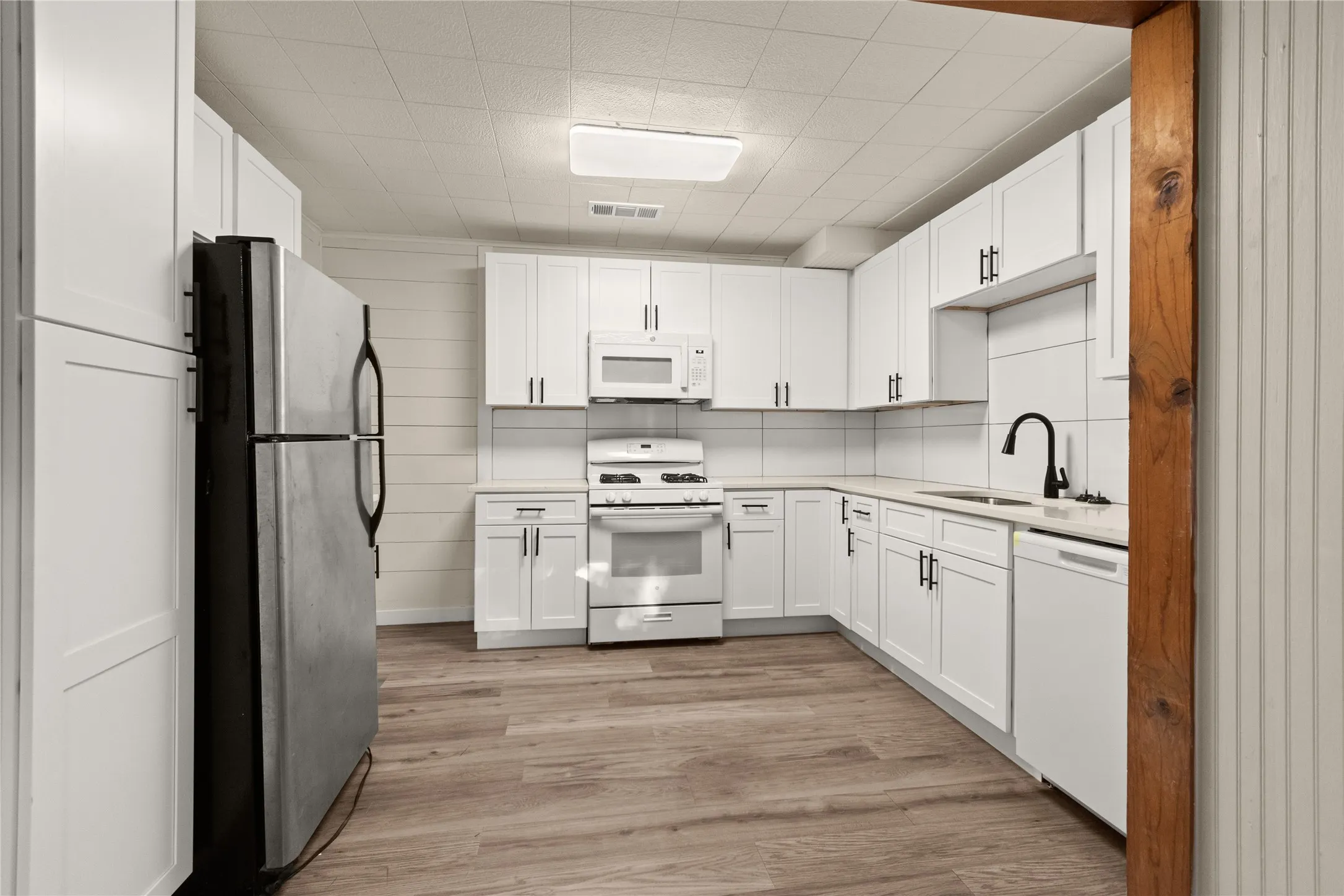 Kitchen featuring white shaker cabinetry, quartz countertops, white range, wood-finish flooring, and a matte black faucet