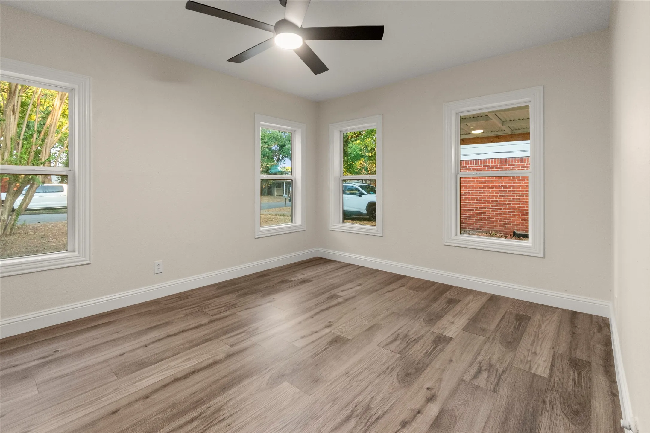 Bedroom #1 with Neutral wall color, wood-finish flooring, multiple windows, white trim, and a ceiling fan with integrated lighting