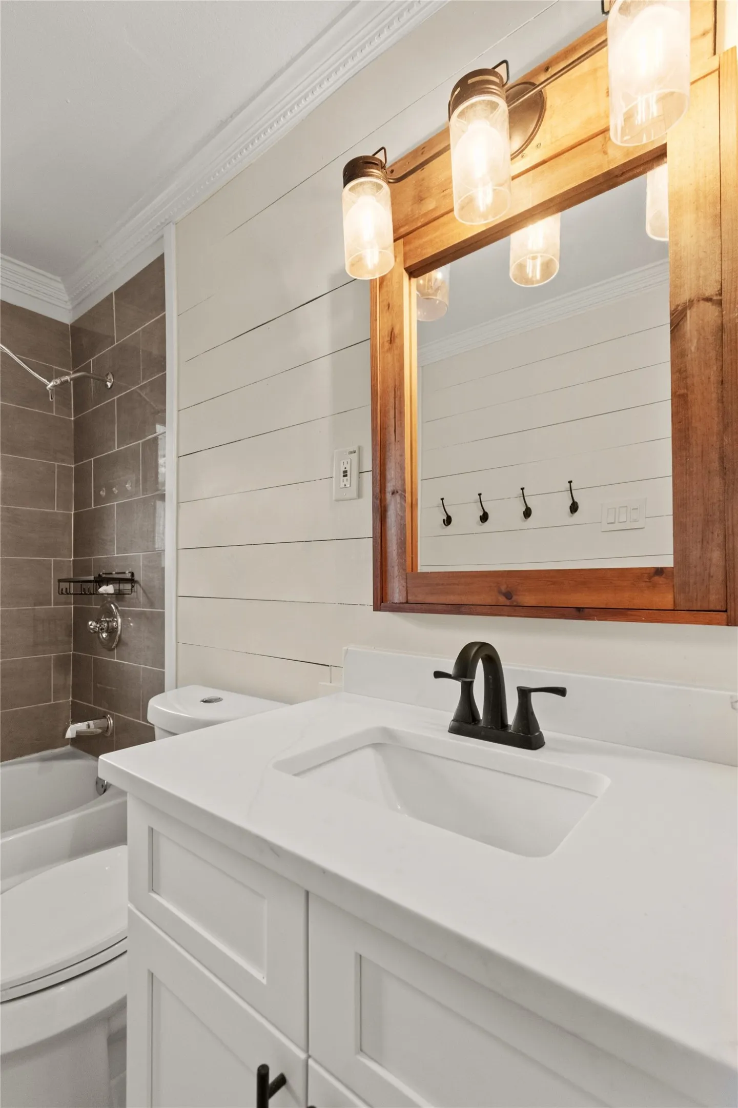 Hallway full-bathroom, white shaker cabinets, quartz countertop, with an integrated sink and black hardware