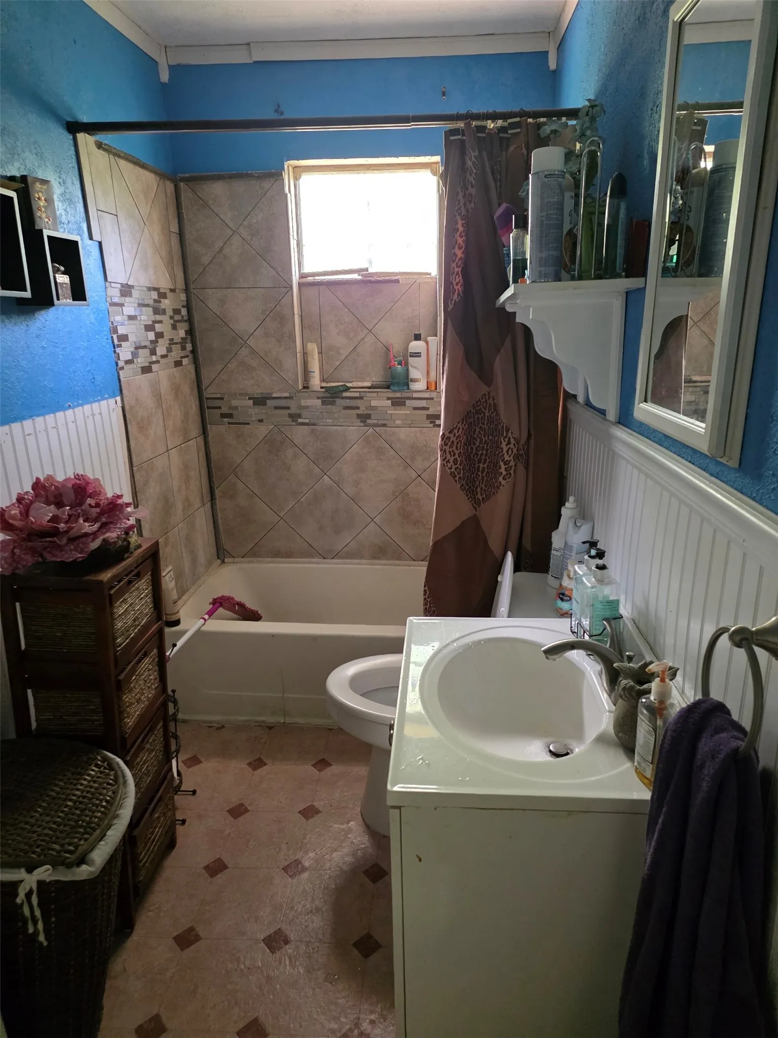 Bathtub with tiled surround, wall-mounted window, and single vanity with integrated sink