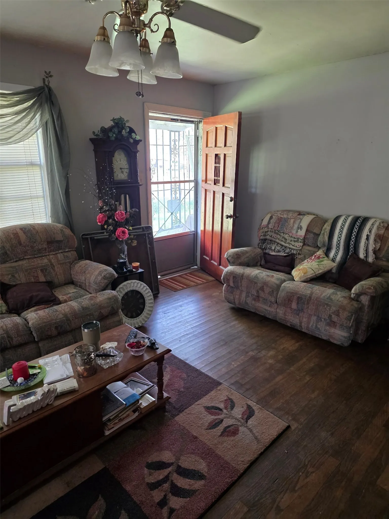 Wood-finish flooring throughout, ceiling fan with integrated lighting, and a solid wood front door