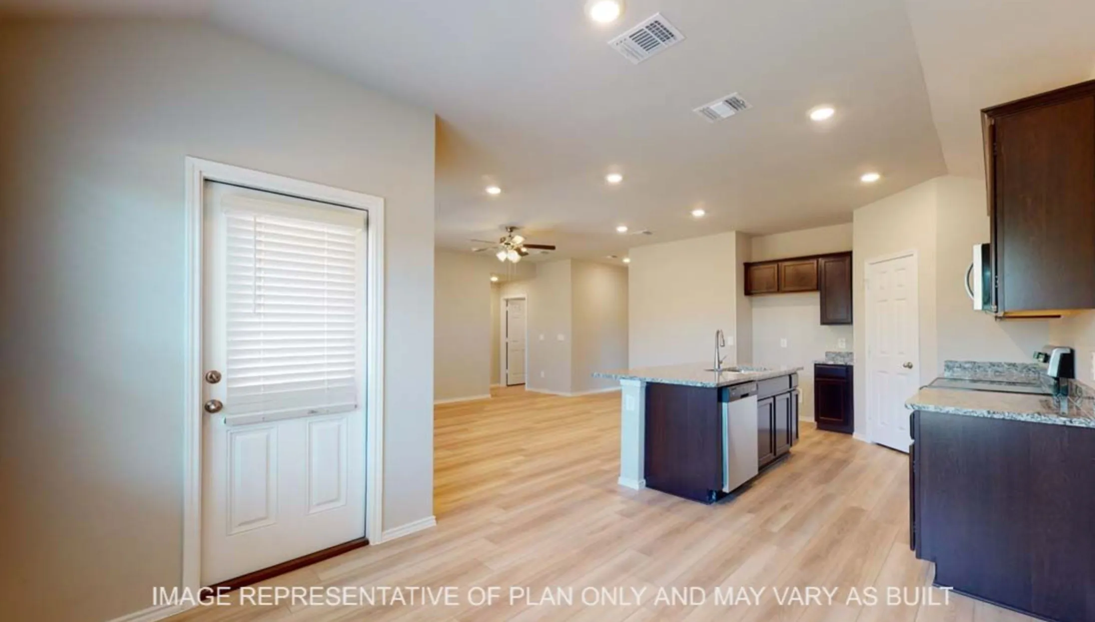 Spacious kitchen featuring dark wood cabinetry, granite countertops, and a central island with an integrated sink and stainless steel dishwasher