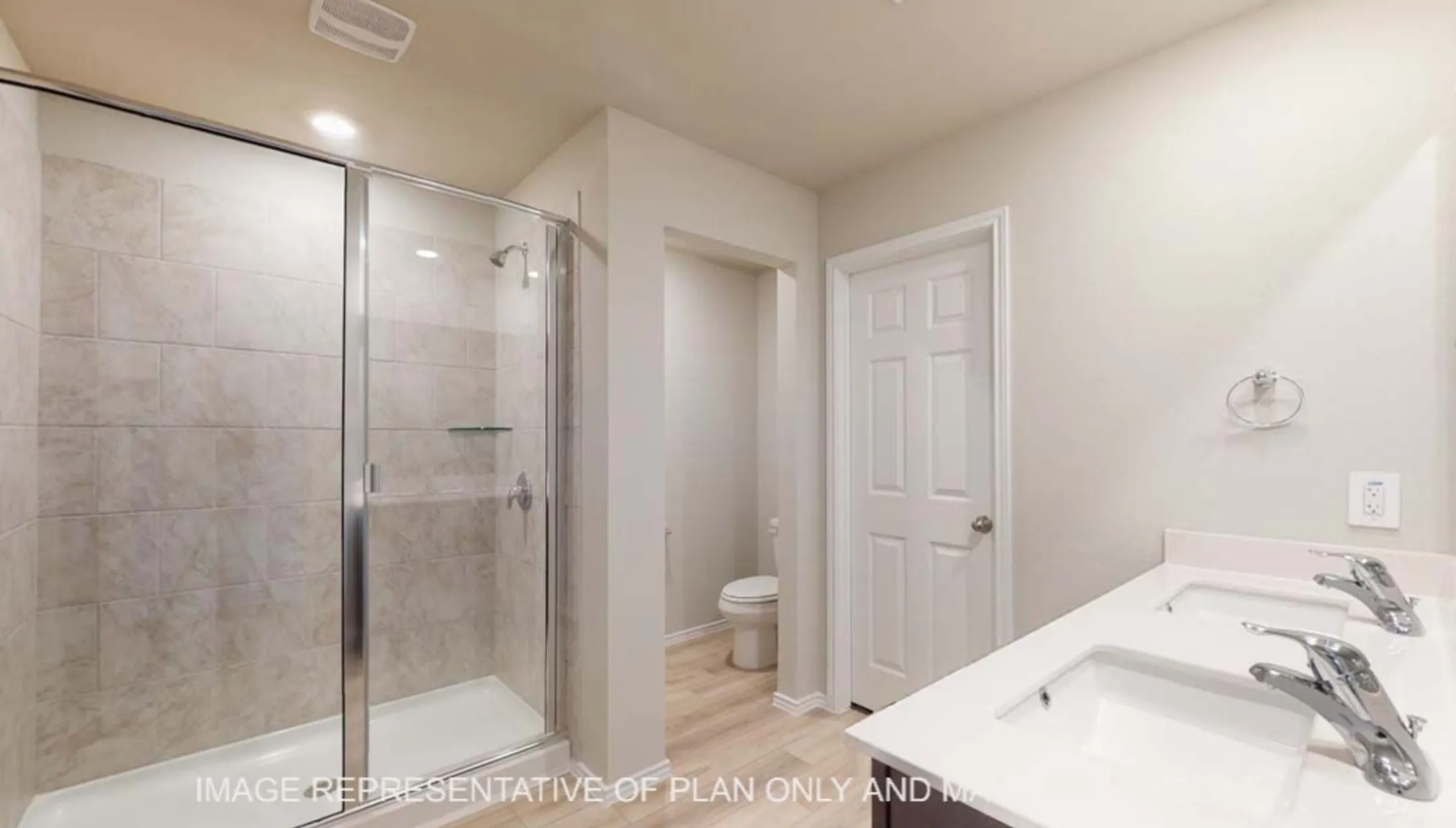 Dual rectangular undermount sinks, spacious countertop, wood-finish flooring, glass-enclosed shower with tile surround, and recessed lighting