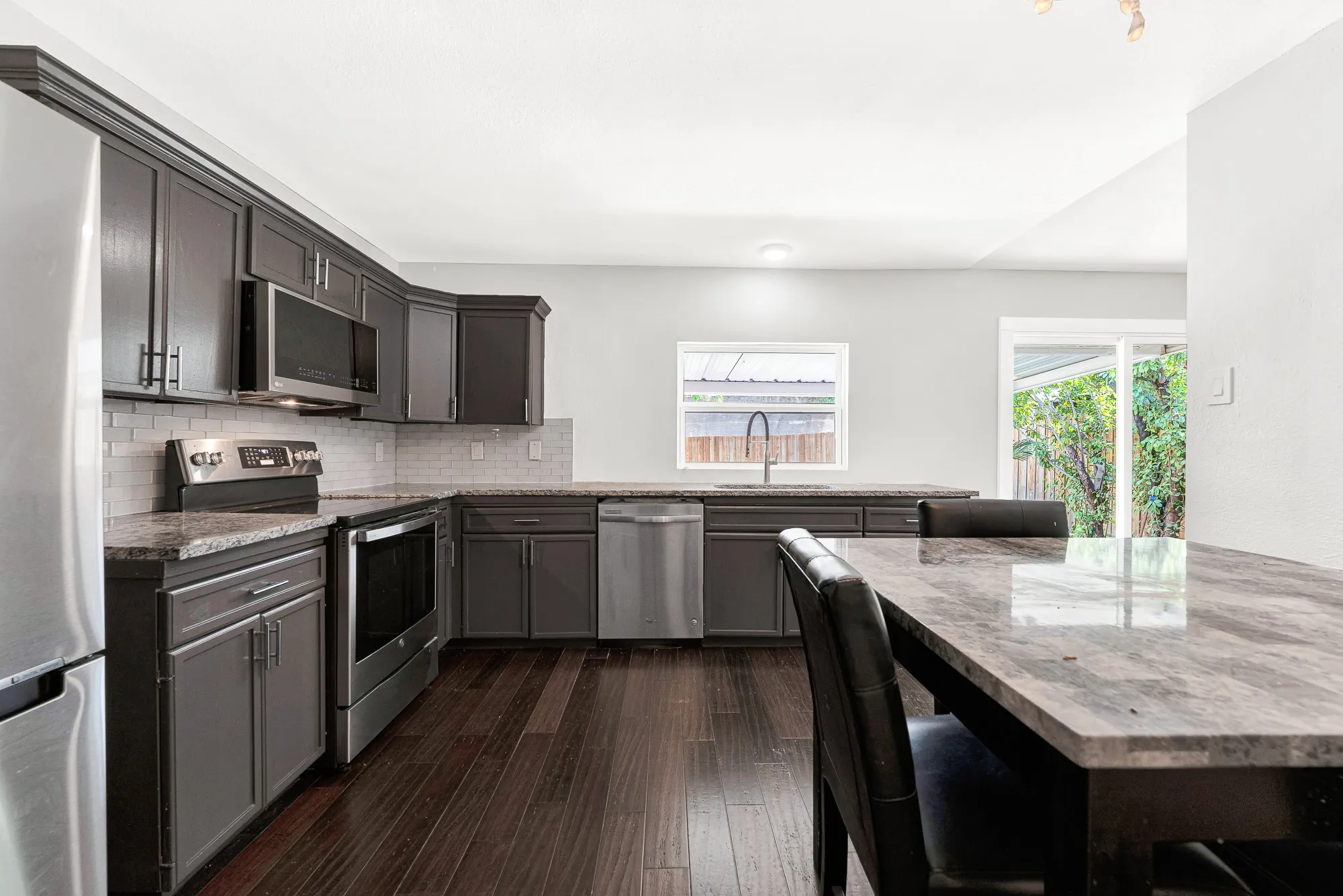 The kitchen’s efficient layout provides abundant counter space and cabinetry, with a window above the sink and direct access to the backyard.