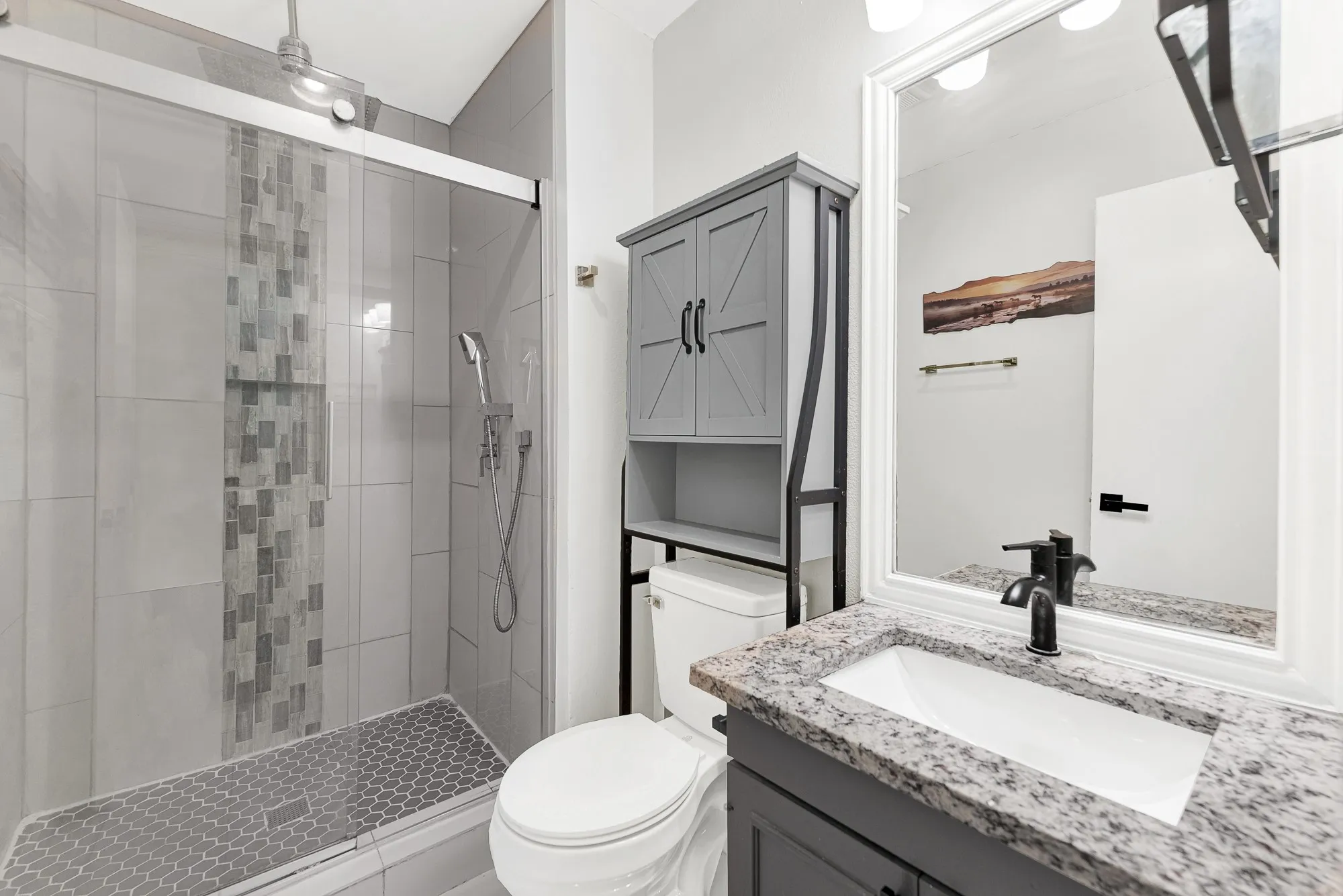Updated primary bathroom with granite countertop and custom shower.