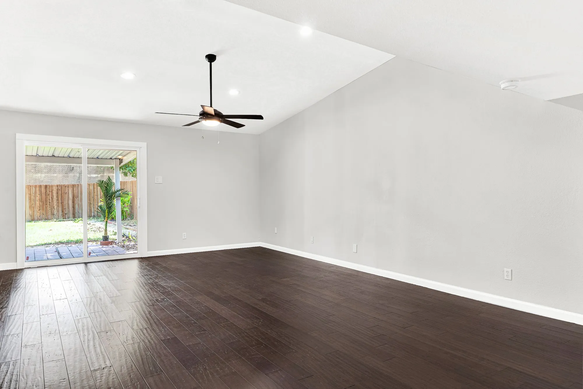 Large living room with high ceilings, engineered wood floors and access to the backyard.