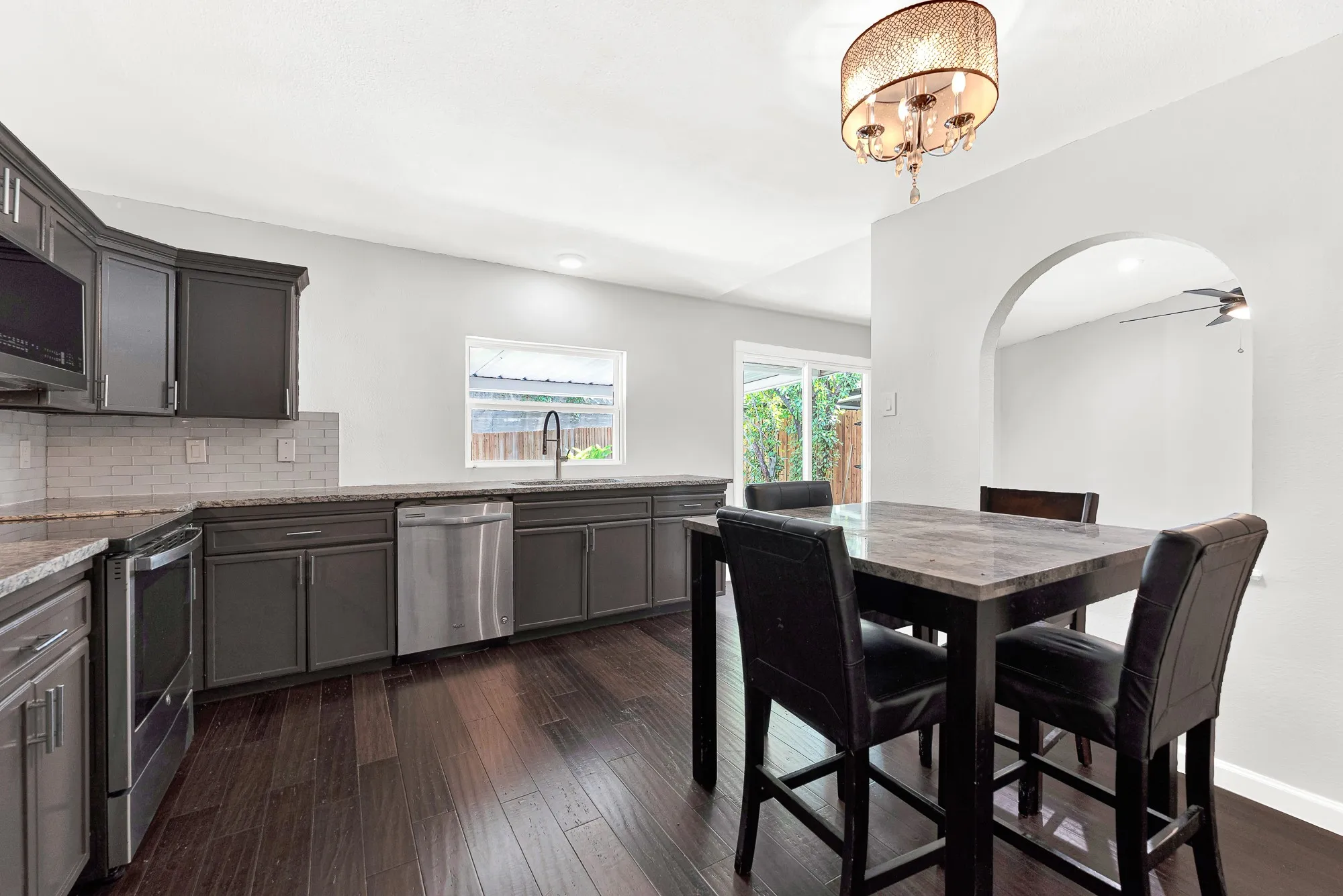 The adjoining dining area creates an easy flow between cooking and gathering spaces, accented by a decorative light fixture and charming arched opening.