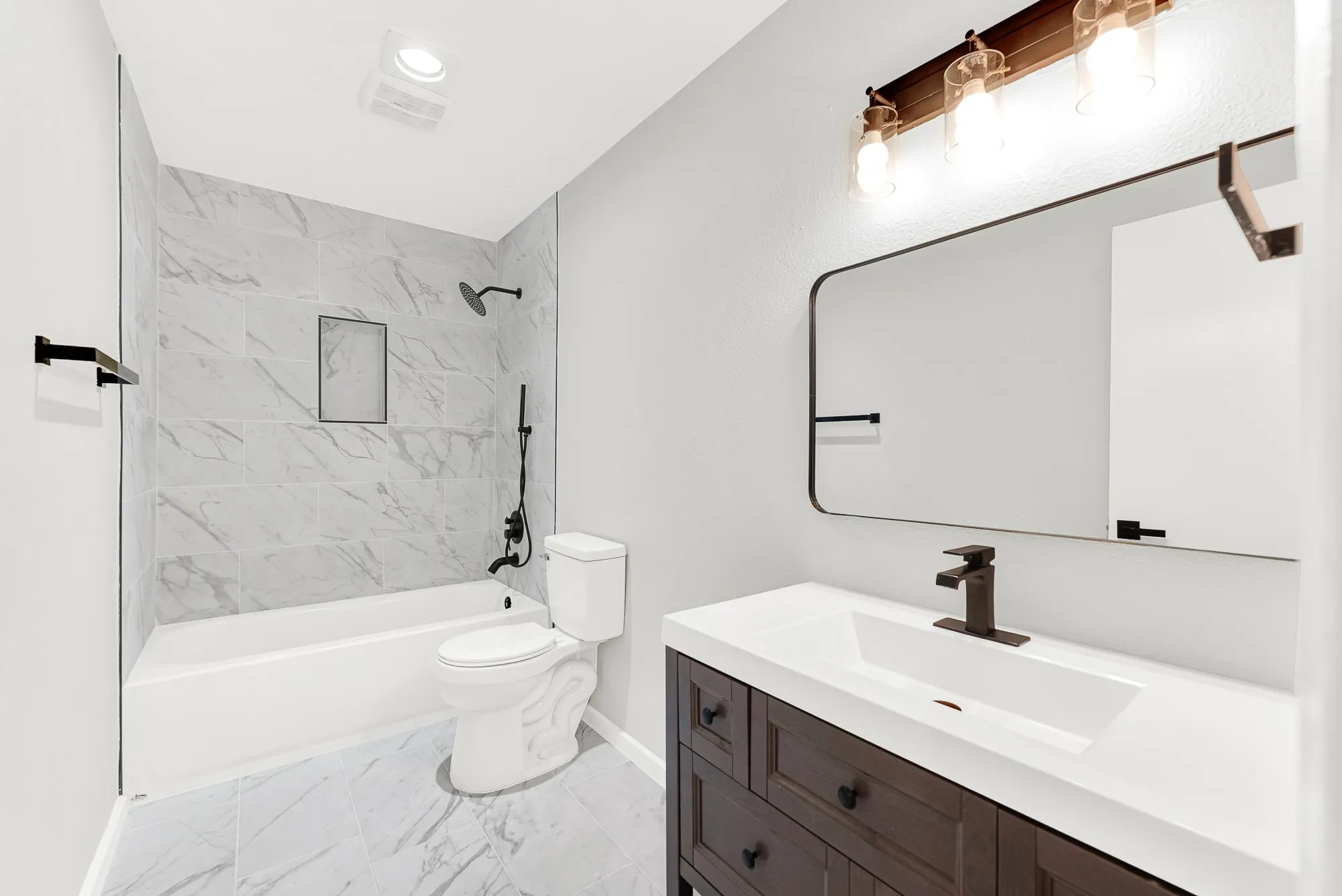 Full bathroom with updated cabinet, tile, lights and fixtures.