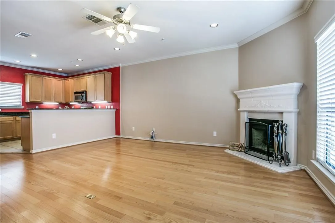 Wood-finish flooring throughout, featuring a corner fireplace with a decorative mantel and hearth