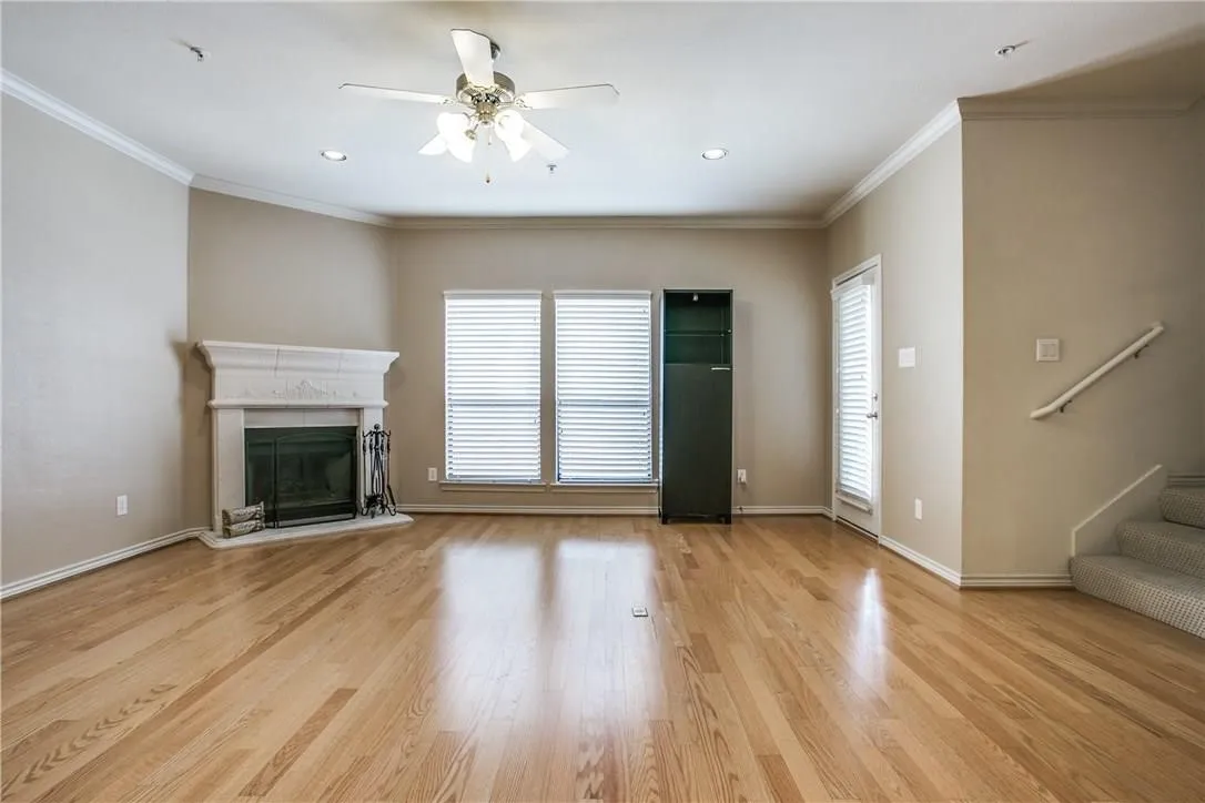 Wood-finish flooring, crown molding, and a fireplace with a decorative mantel enhance the living space