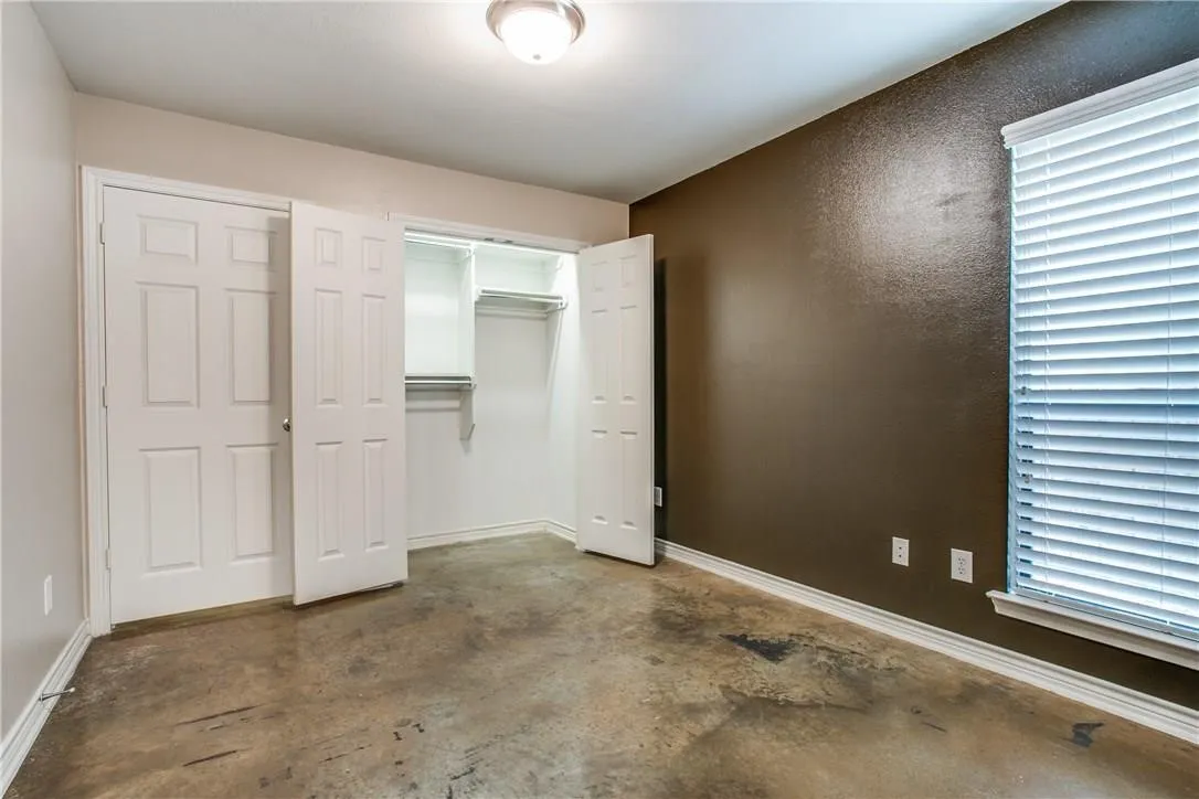 Expansive flooring, dual closet doors with six-panel design, interior closet shelving, and a prominent window with blinds