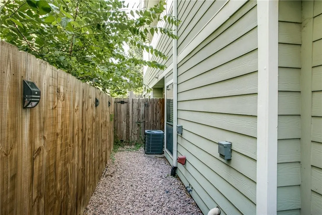 Wood privacy fence with solar-powered wall lights, horizontal siding exterior, and a gravel pathway