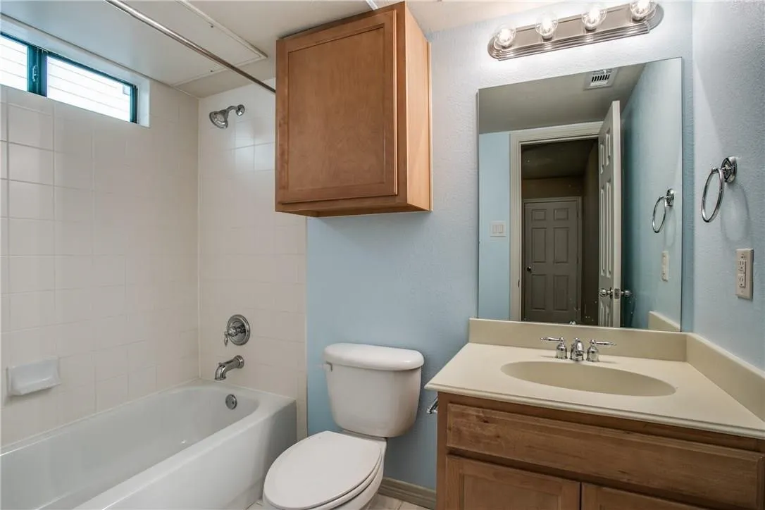 White tiled bathtub/shower combination with a transom window