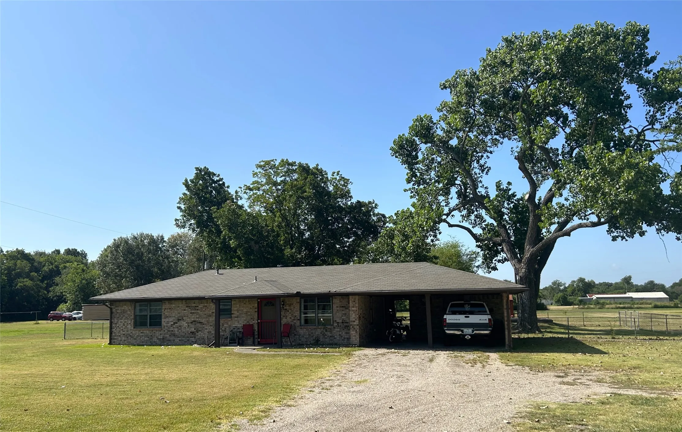Front of home with large cottonwood tree in the back and 2 car carport