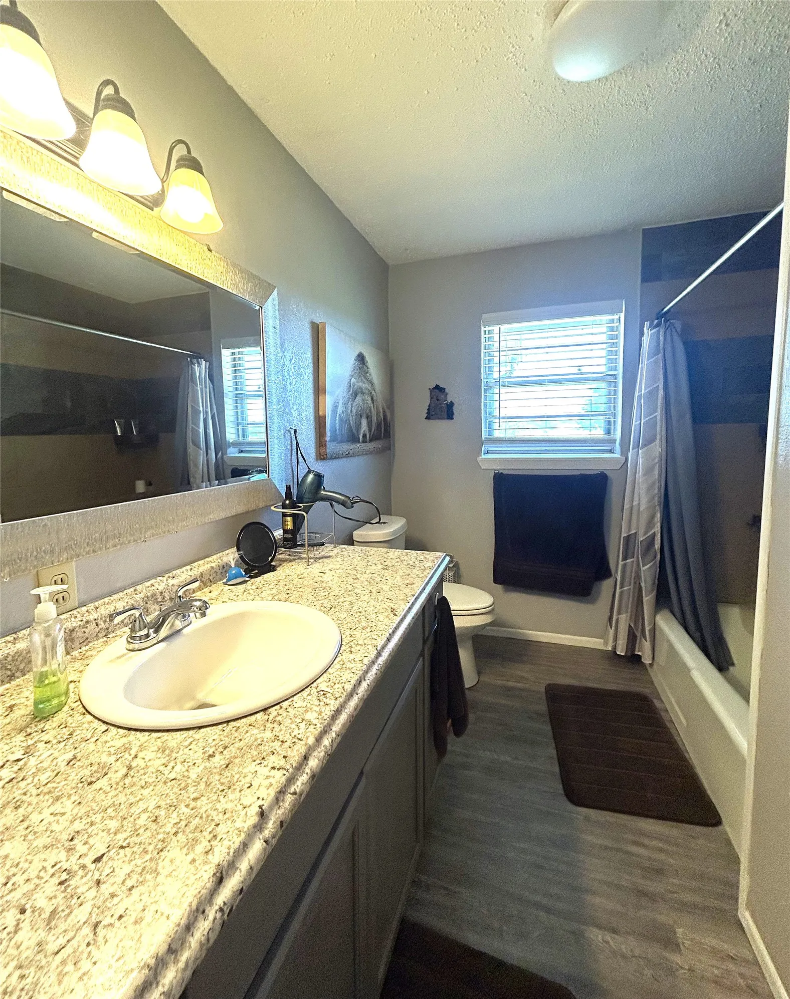 Nice size bathroom with plenty of light, a large sink area and a linen closet behind the door