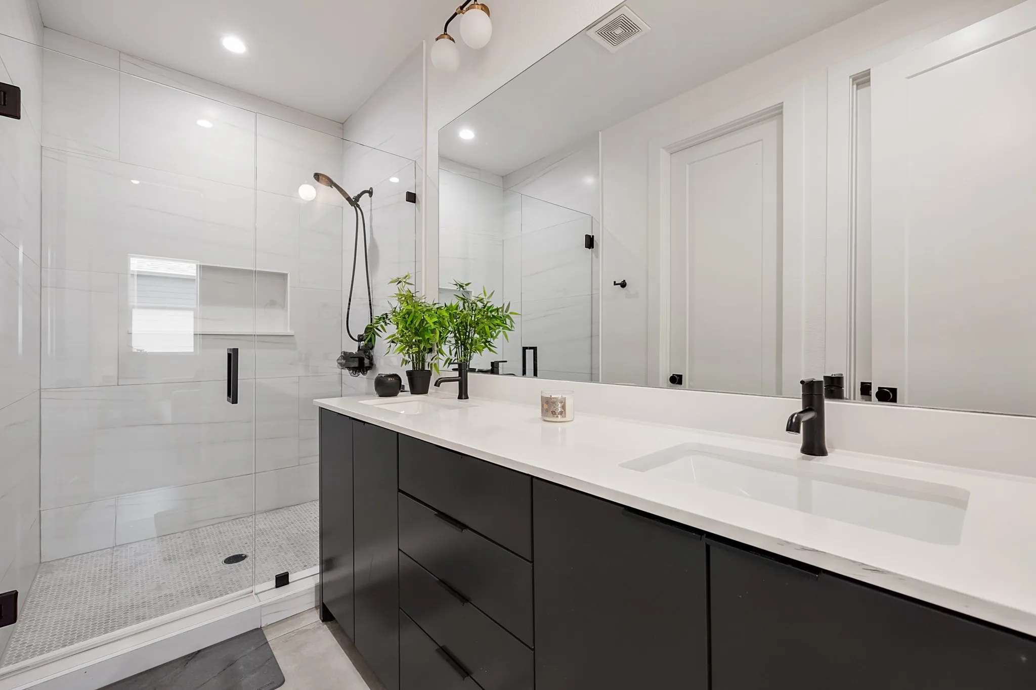 Dual sink vanity with white countertop, matte black fixtures, and a frameless mirror