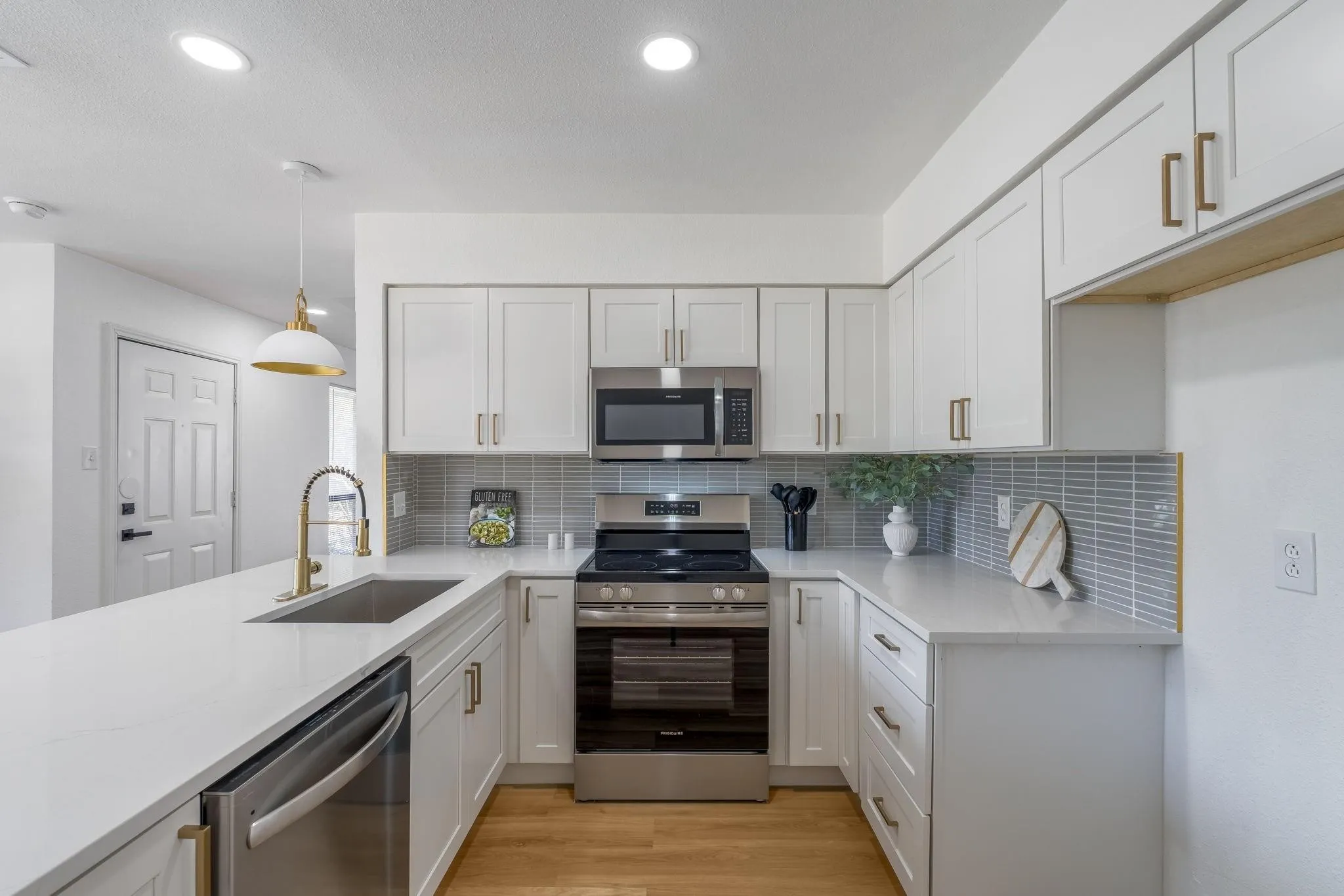 U-shaped kitchen with white cabinetry and gold-tone hardware