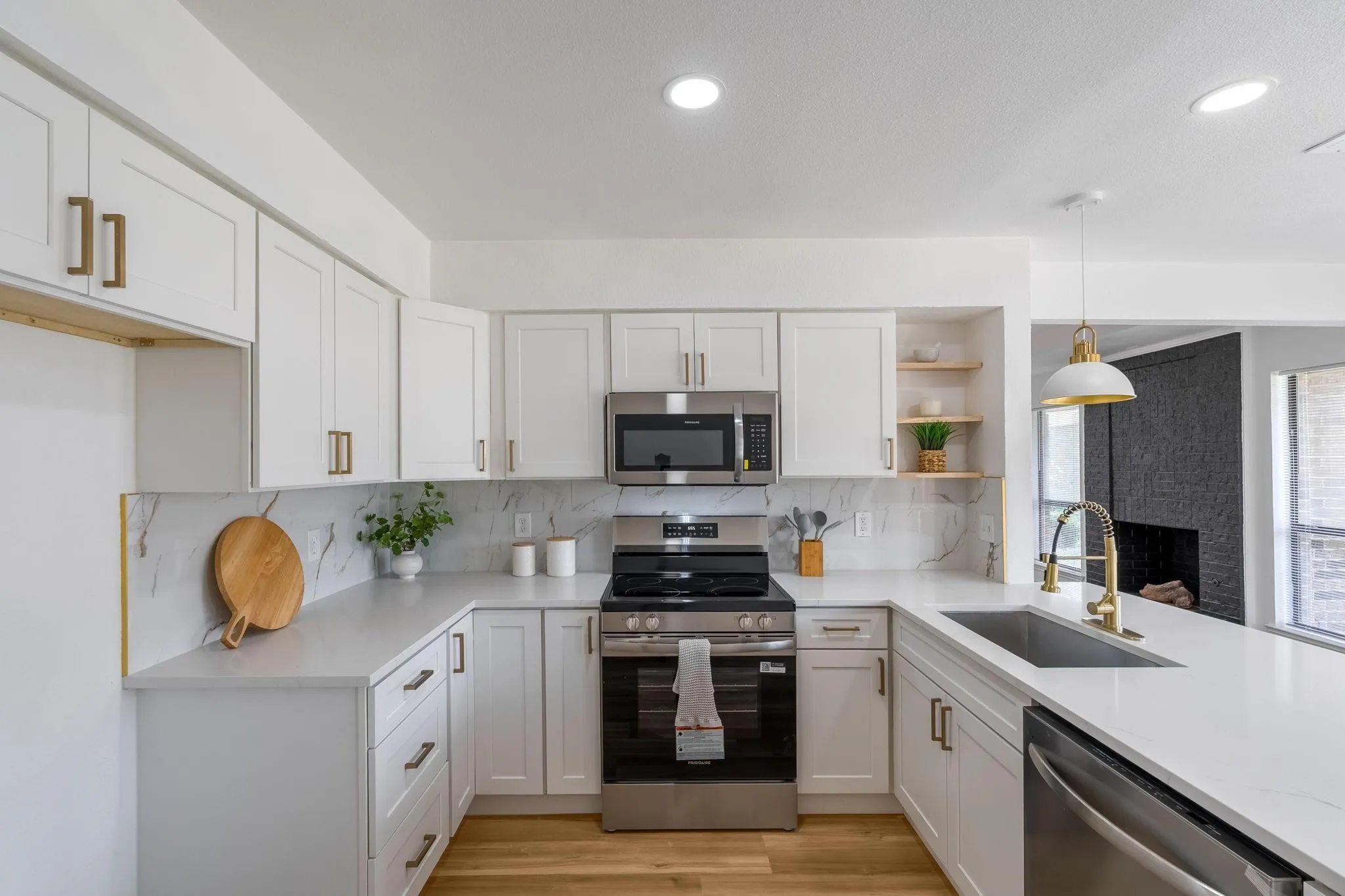 U-shaped kitchen featuring white cabinetry, light-toned countertops, stainless steel appliances, and a full-height backsplash
