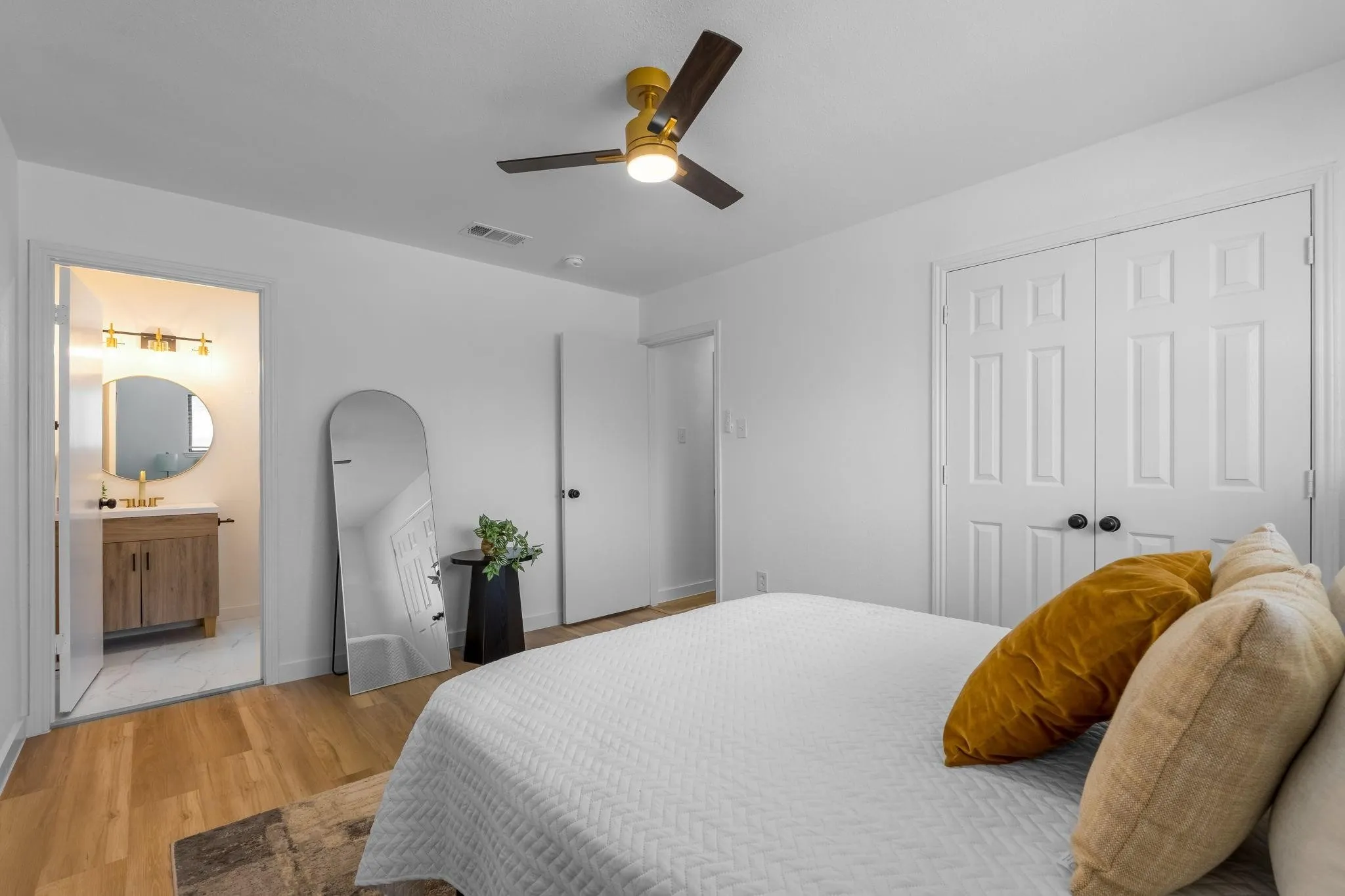 Wood-finish flooring, white panel doors, and a ceiling fan with integrated lighting