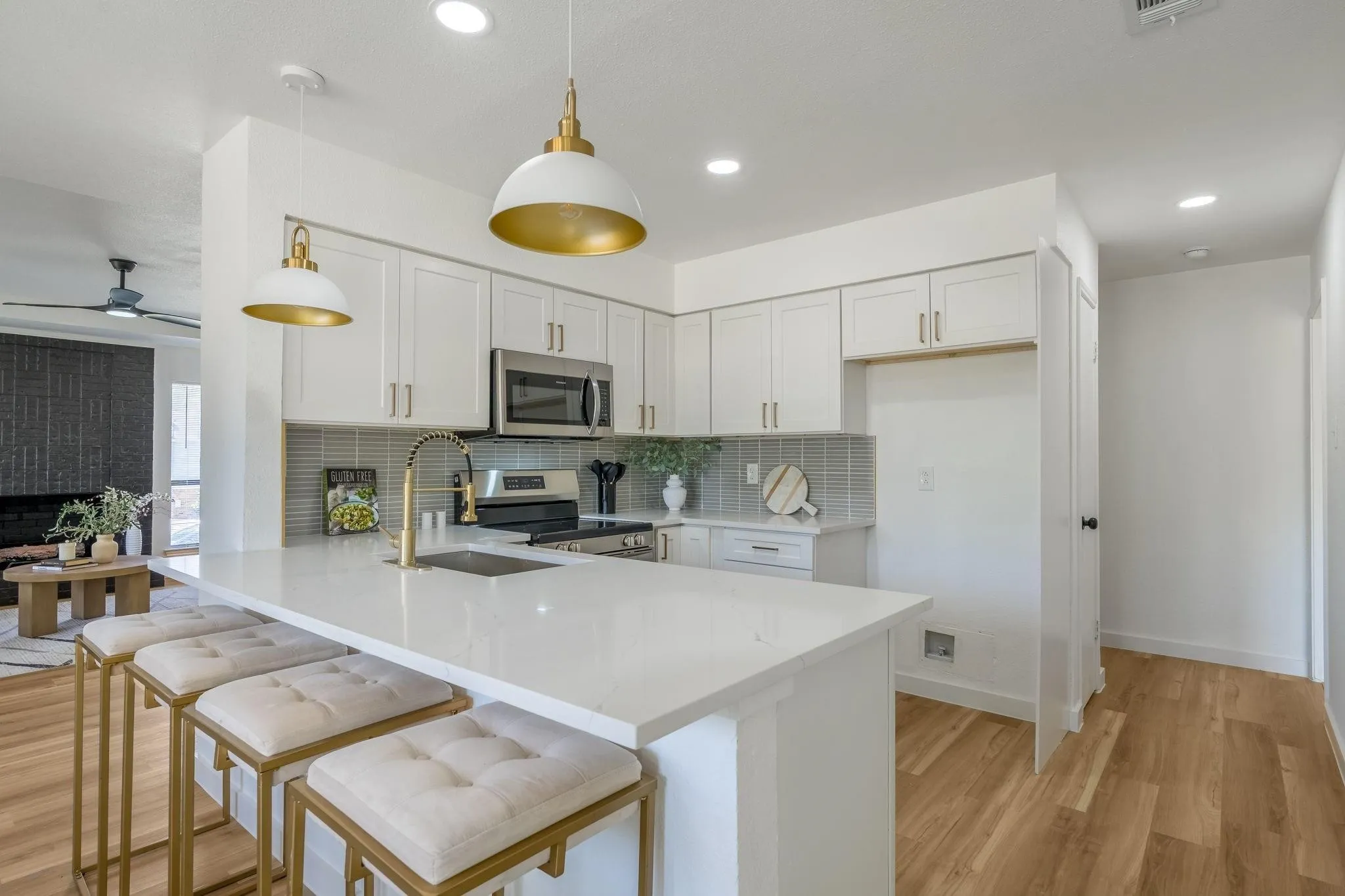 Kitchen featuring white cabinetry, stainless steel appliances, a white countertop island, and wood-finish flooring
