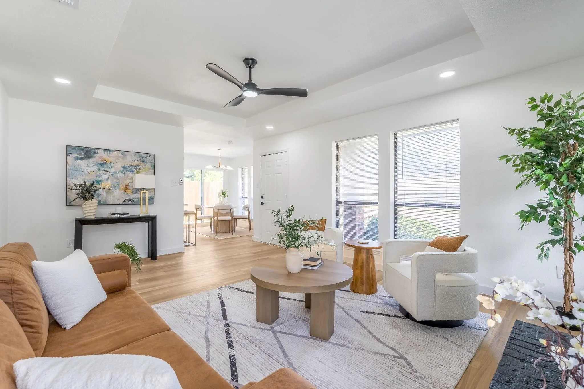 Recessed lighting, light wood-finish flooring, tray ceiling, and a ceiling fan with integrated lighting
