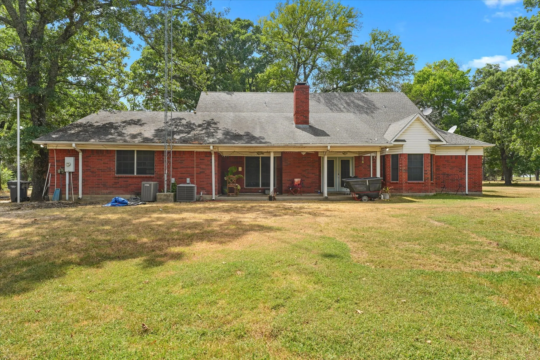 Brick exterior with a covered patio, a prominent chimney, and a gabled roofline