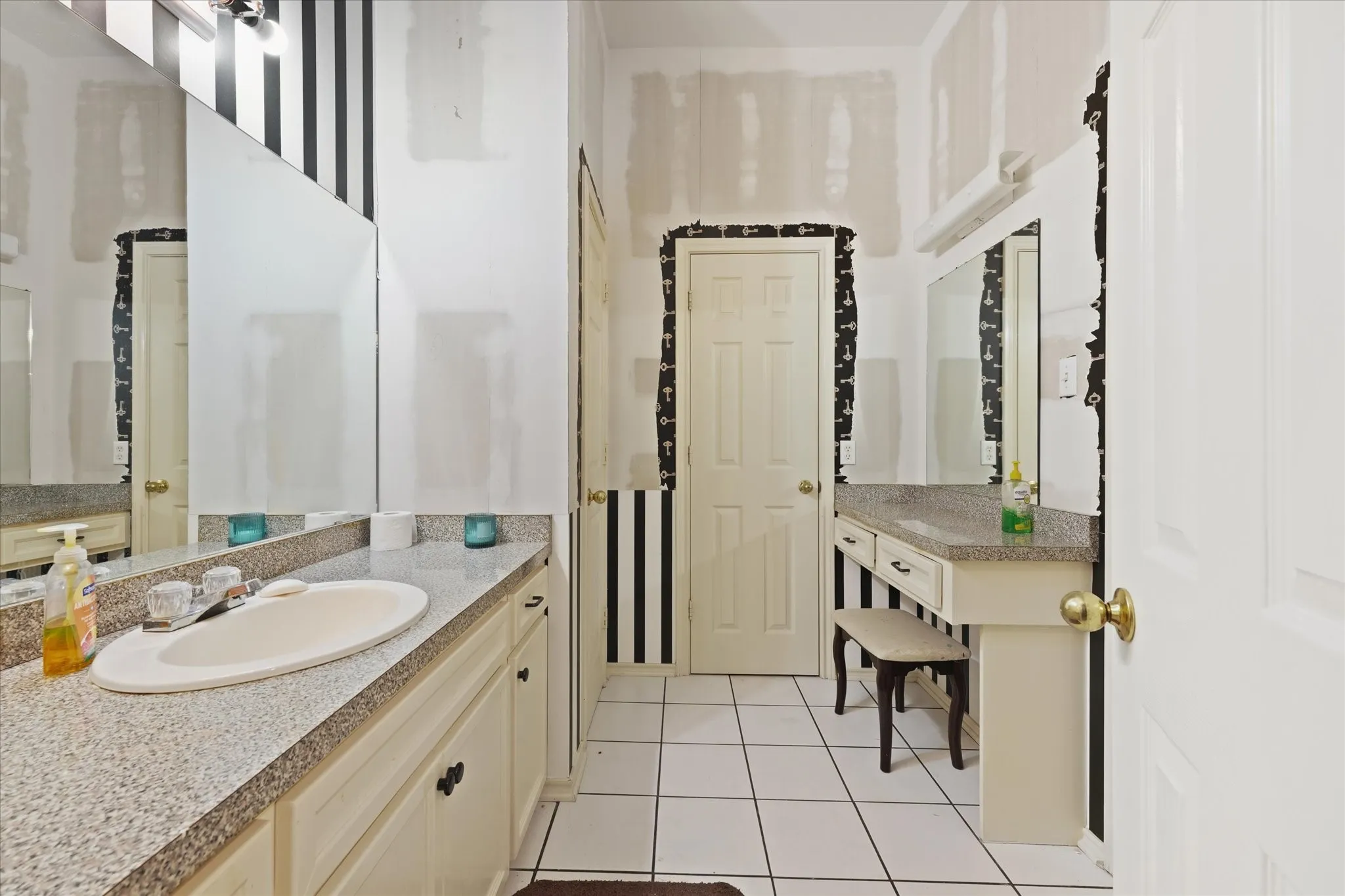 White tile flooring, dual vanities with integrated sinks, light-toned countertops, and a dedicated vanity area