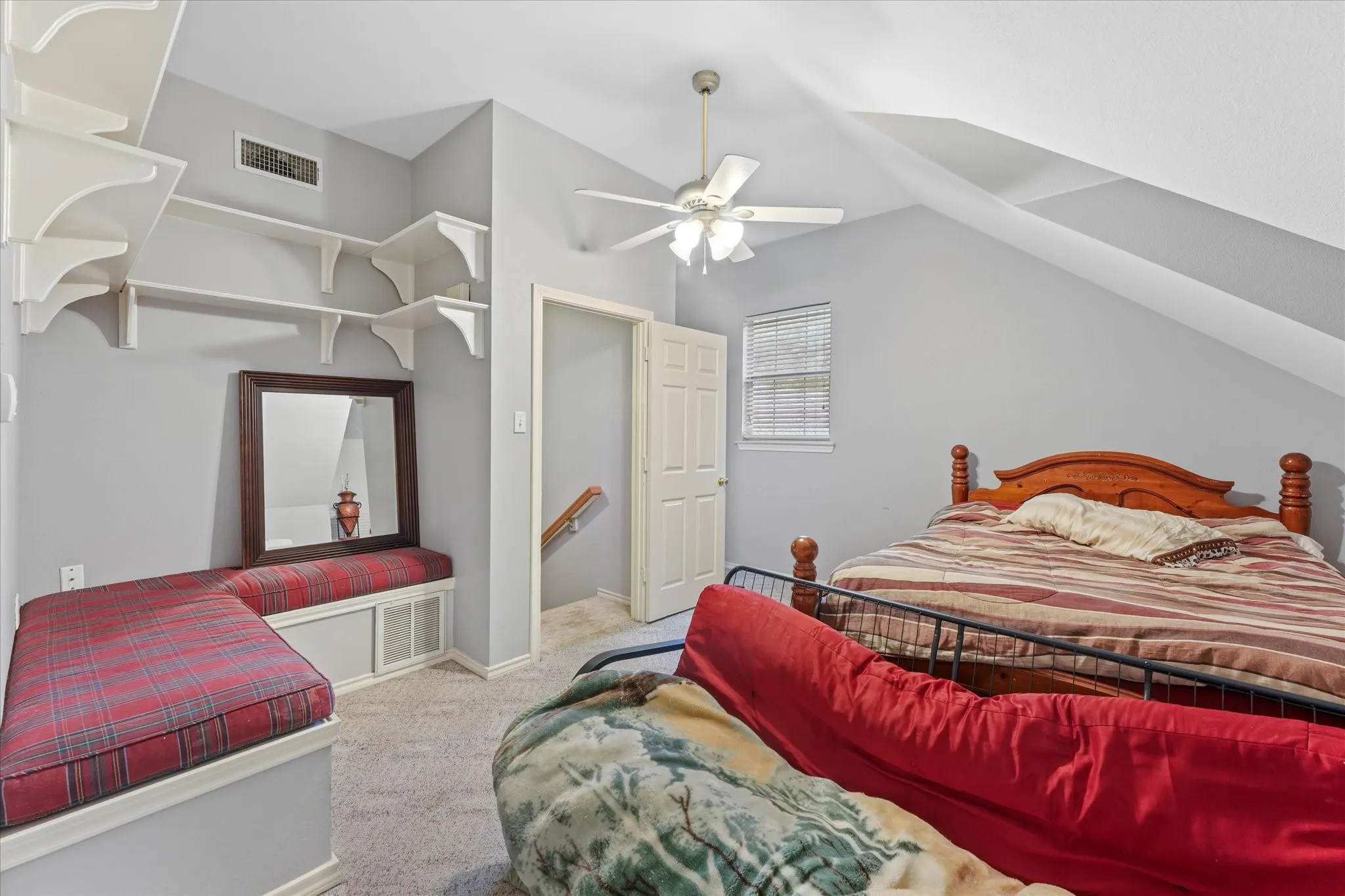 Sloped ceiling design, built-in shelving, integrated window bench, ceiling fan, and carpet flooring