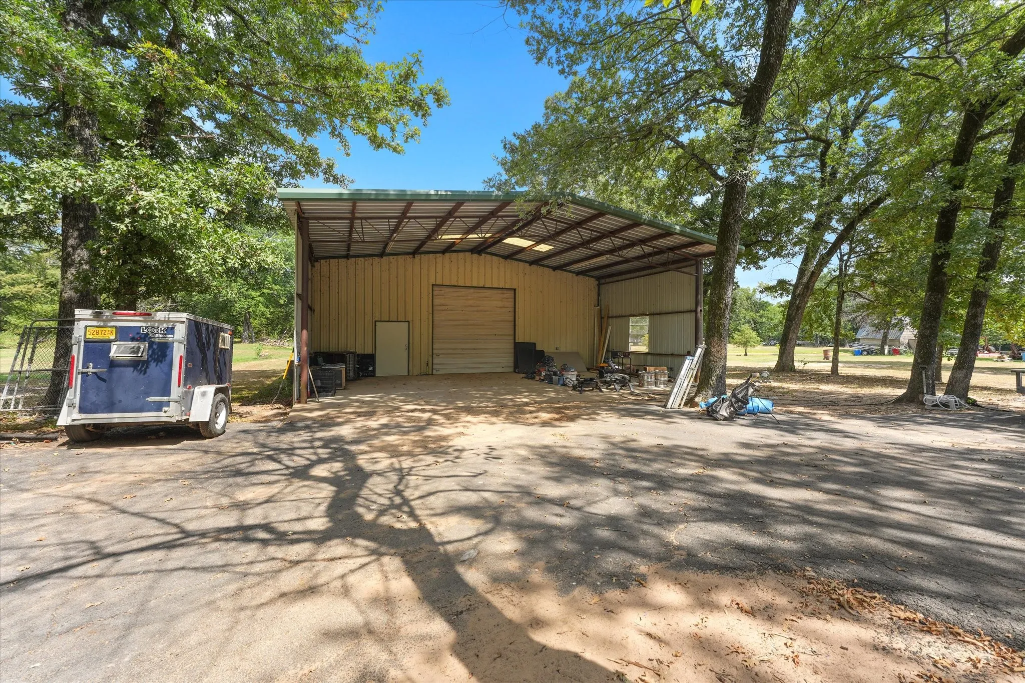 Metal-sided structure with a covered parking area, large roll-up door, and an additional personnel door