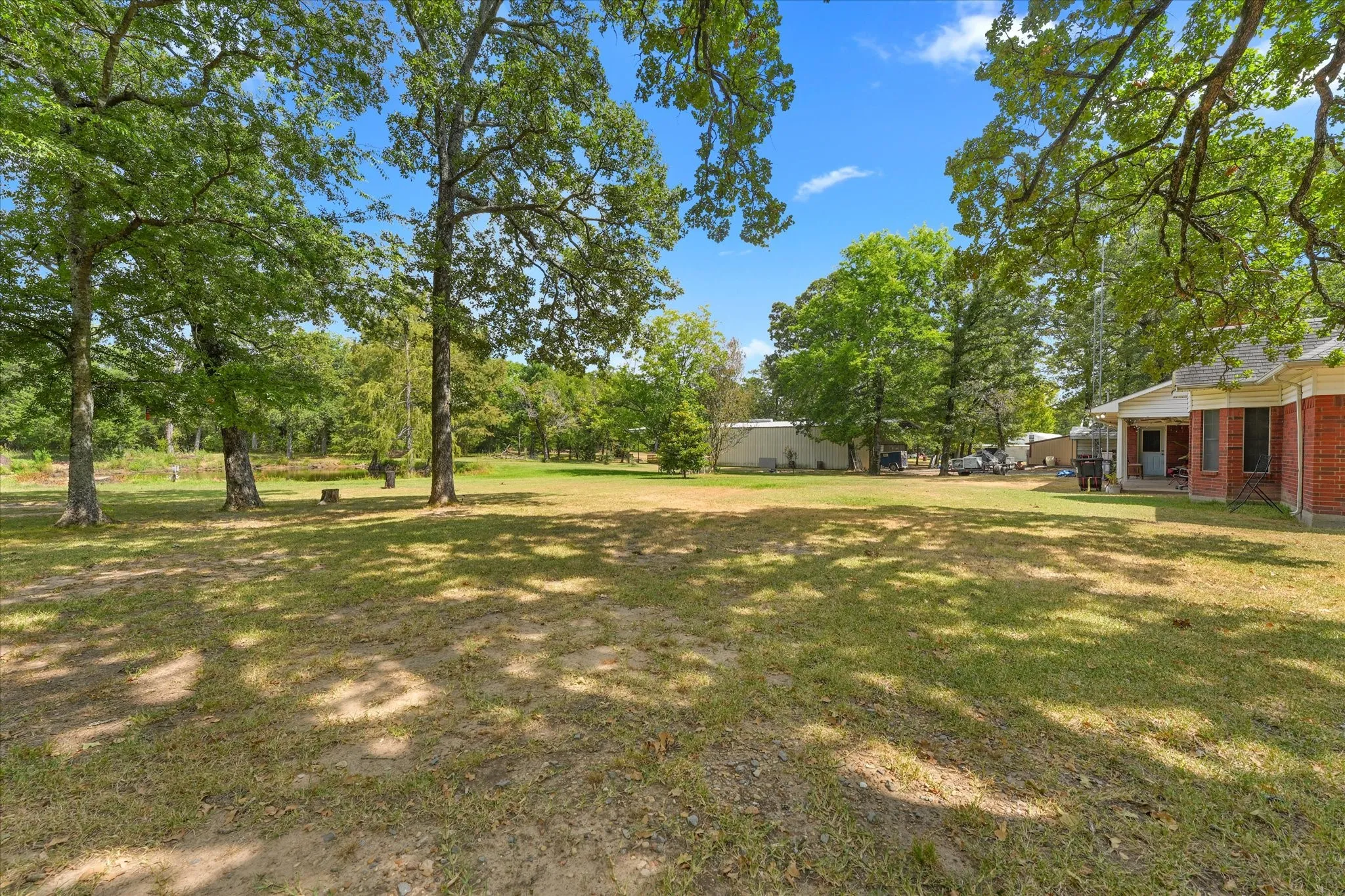 Expansive grass lawn featuring mature trees and a brick-clad exterior
