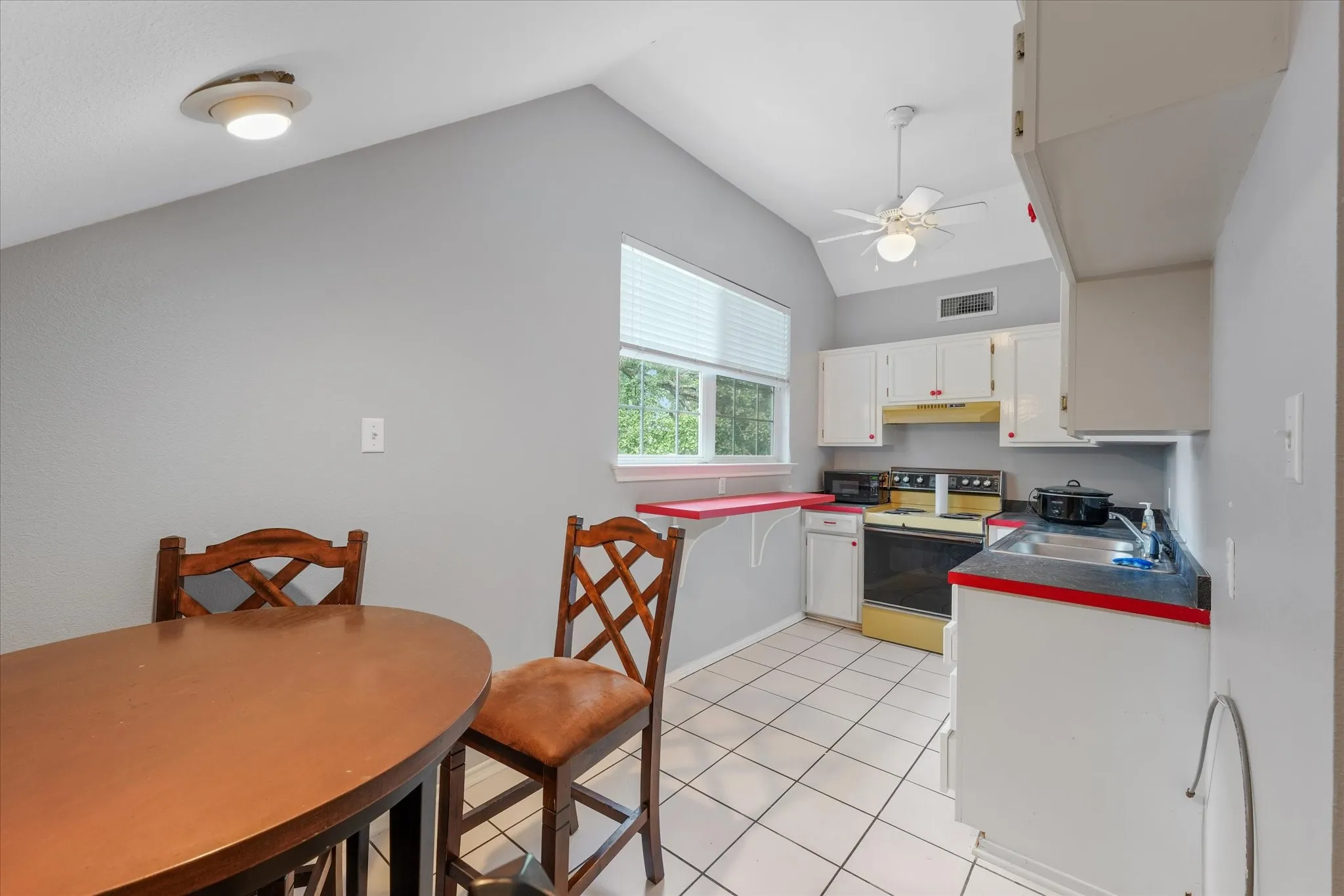 Kitchen featuring white cabinetry, tiled flooring, an electric range, and a single basin sink