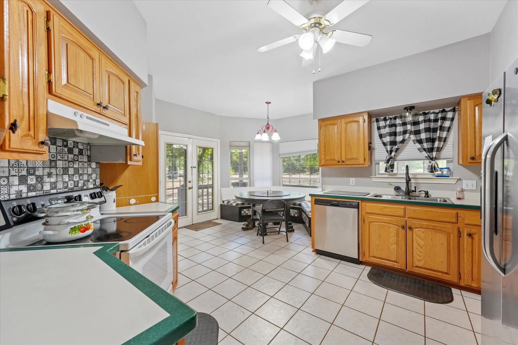 Kitchen featuring light wood cabinetry, white tile flooring, a built-in banquette, and stainless steel appliances