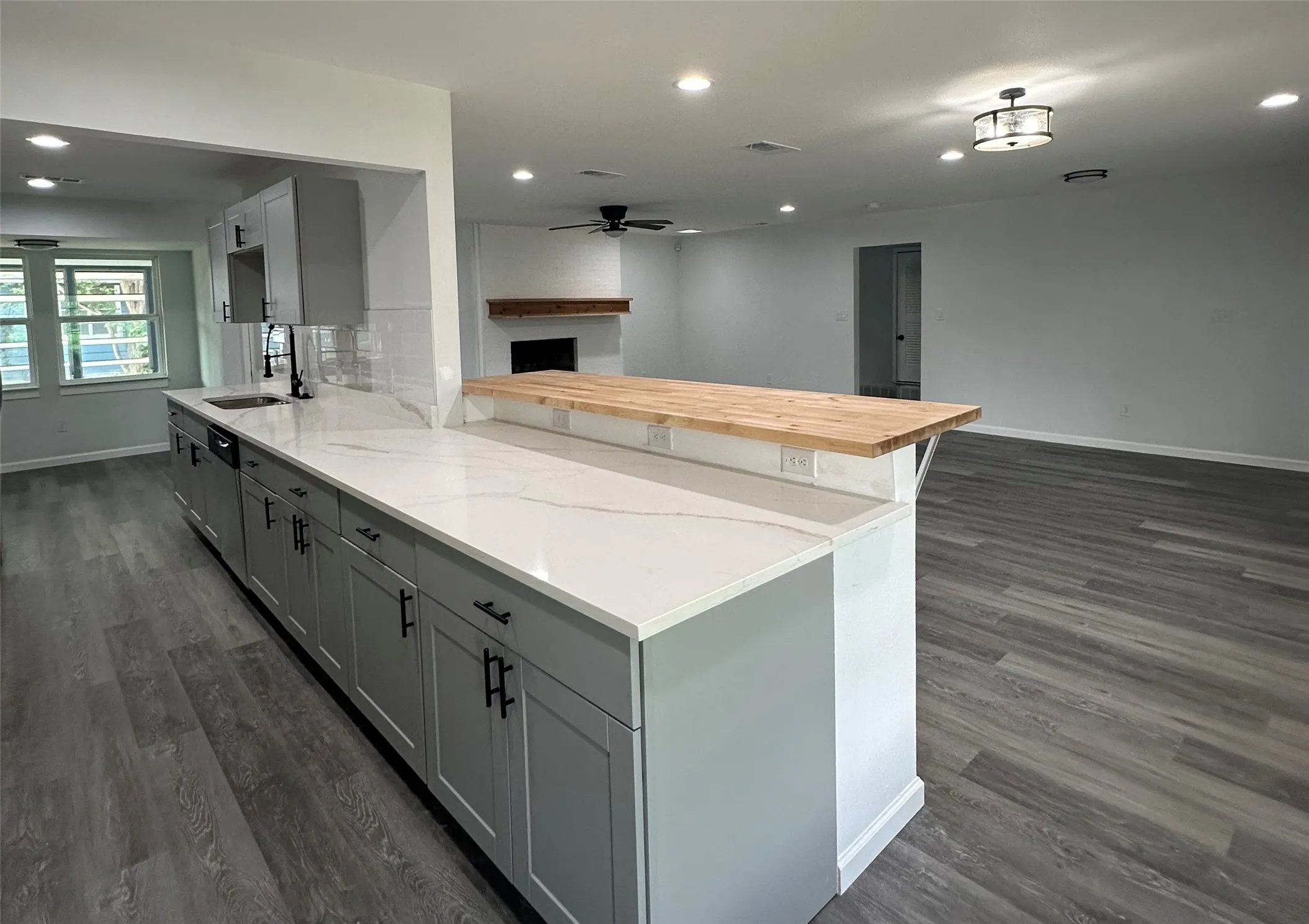 Kitchen featuring gray shaker-style cabinetry, a white quartz countertop, a subway tile backsplash, and a wood-finish breakfast bar